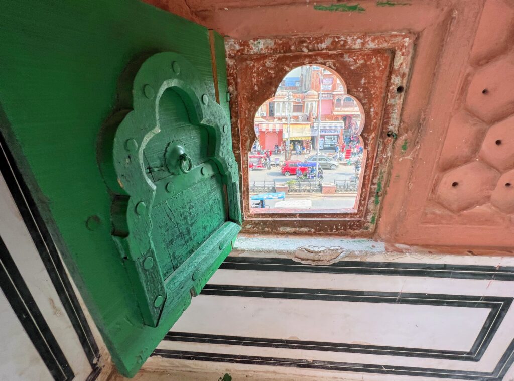A green jharoka opening into the street below.