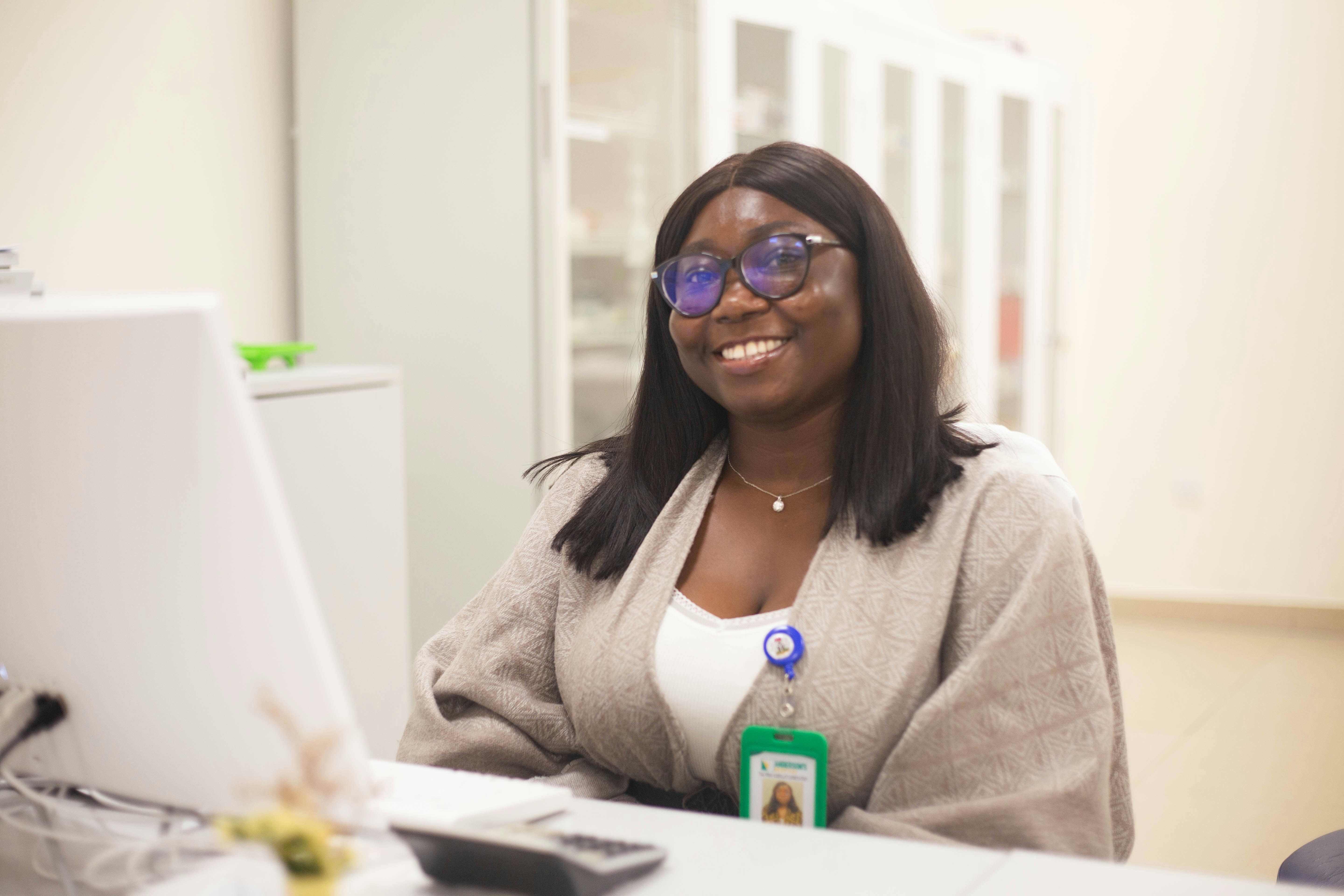 woman sitting while working on laptop and smiling 