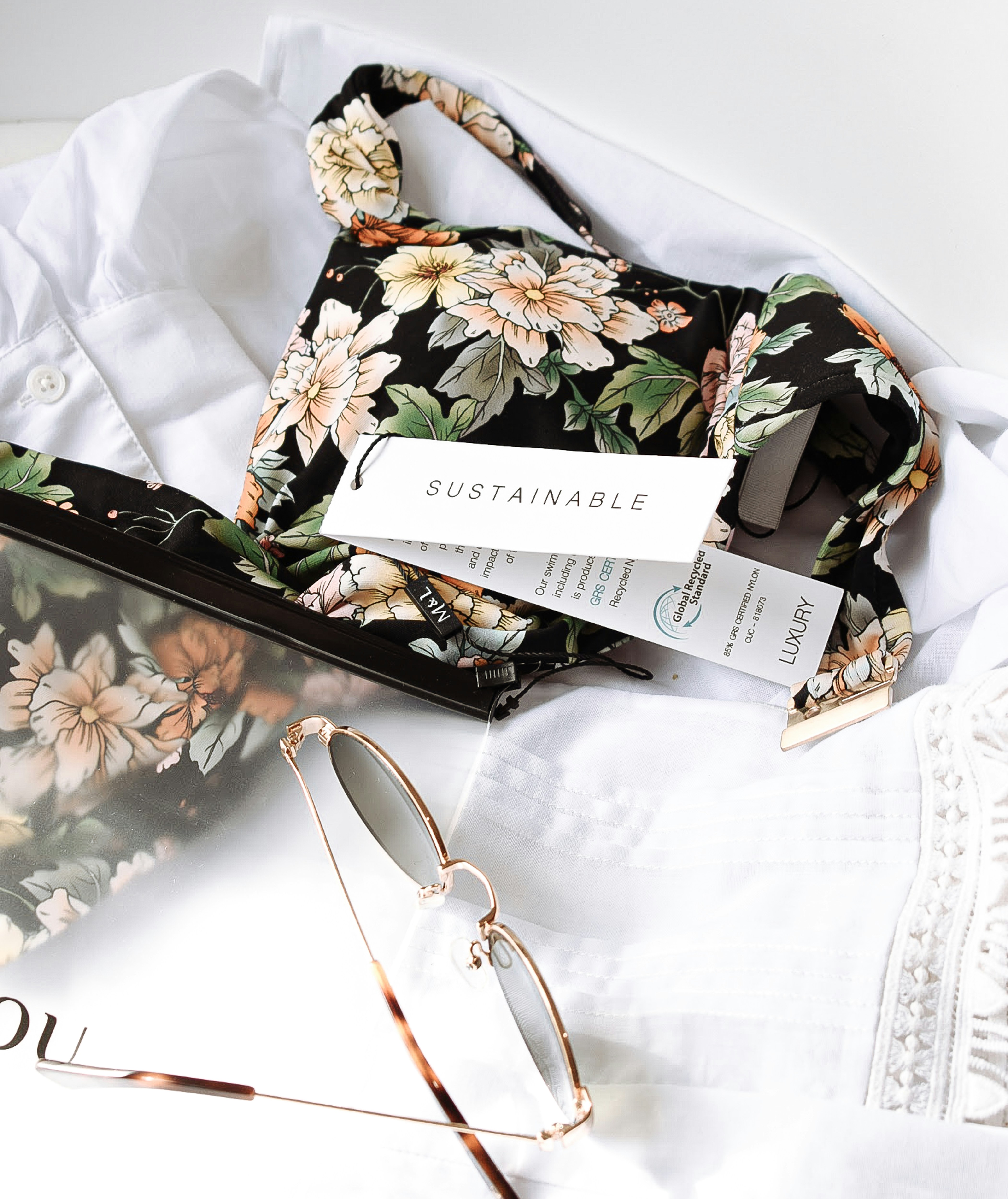 A smiling woman with her arms crossed, standing against a dark green background. She has long, dark hair.