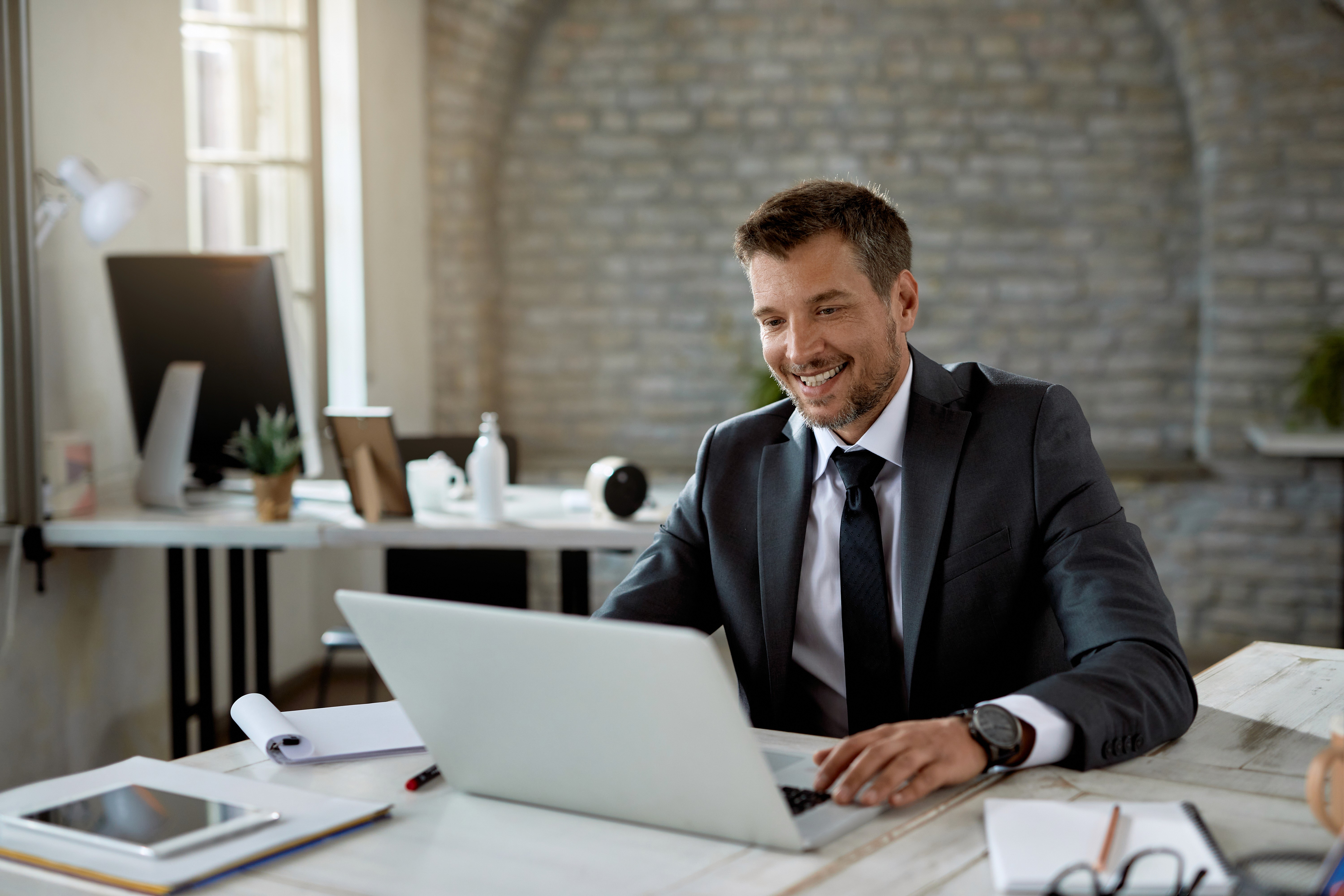 Happy male entrepreneur reading an email on laptop
