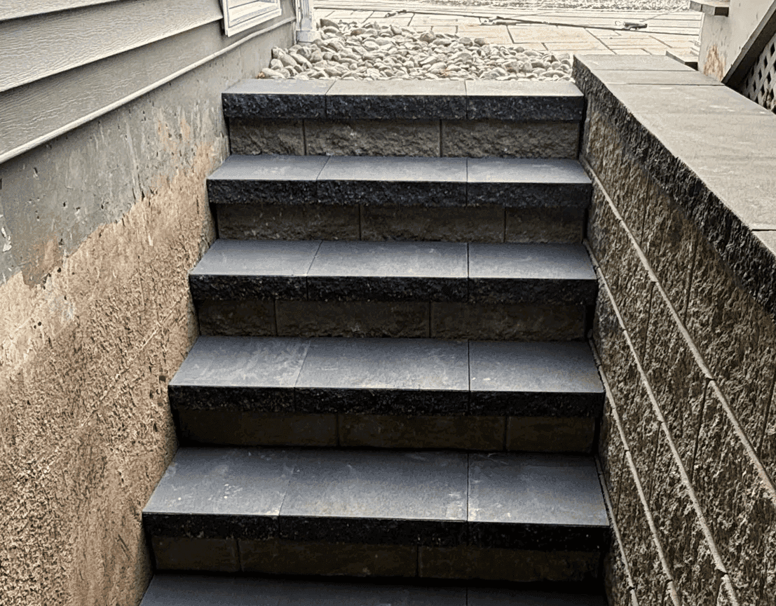 Stone steps descend beside a textured wall.