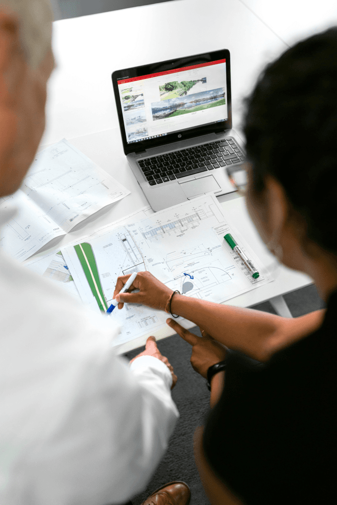 A top-down view of a discovery session, where two instructional designers collaborate over charts and data to create a strategic blueprint for a client's custom learning solution.