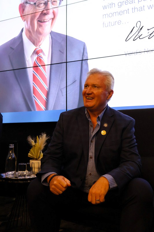 man in a blue suit sits in chair in front of a presentation