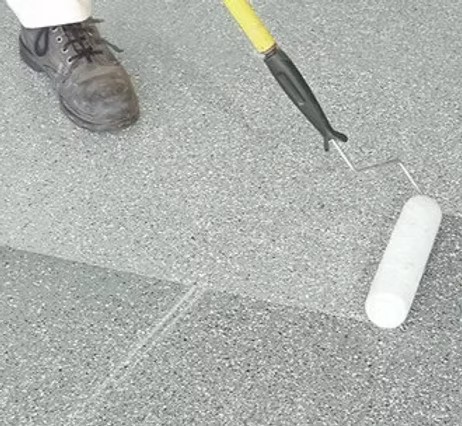 A serene outdoor lounge area with two chairs surrounded by lush greenery and natural light streaming in.