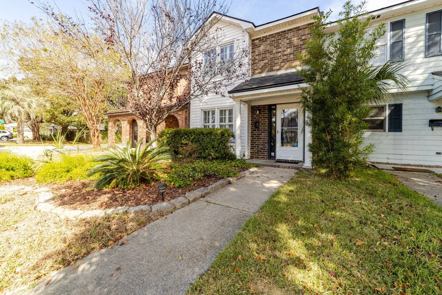 Two-story Mount Pleasant townhome in brick and white siding, with a front walk through the garden