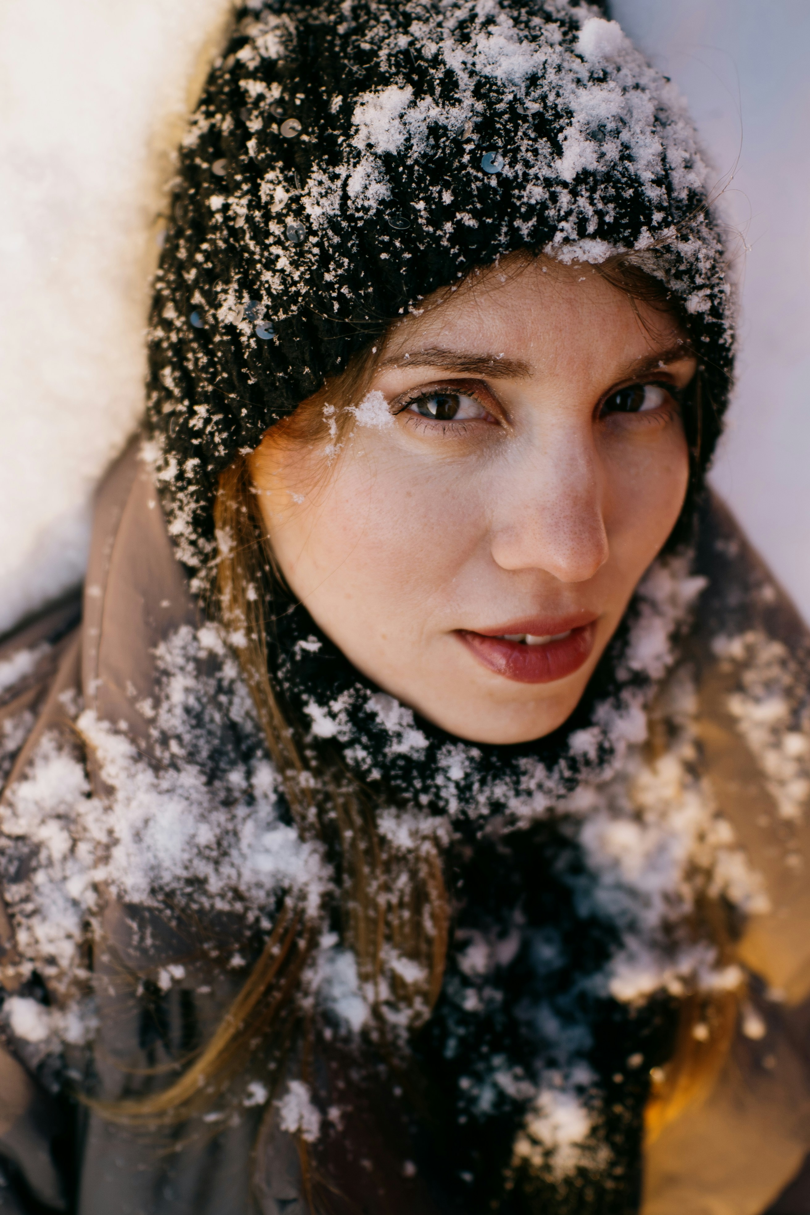 Woman wearing a hat and scarf covered in snow