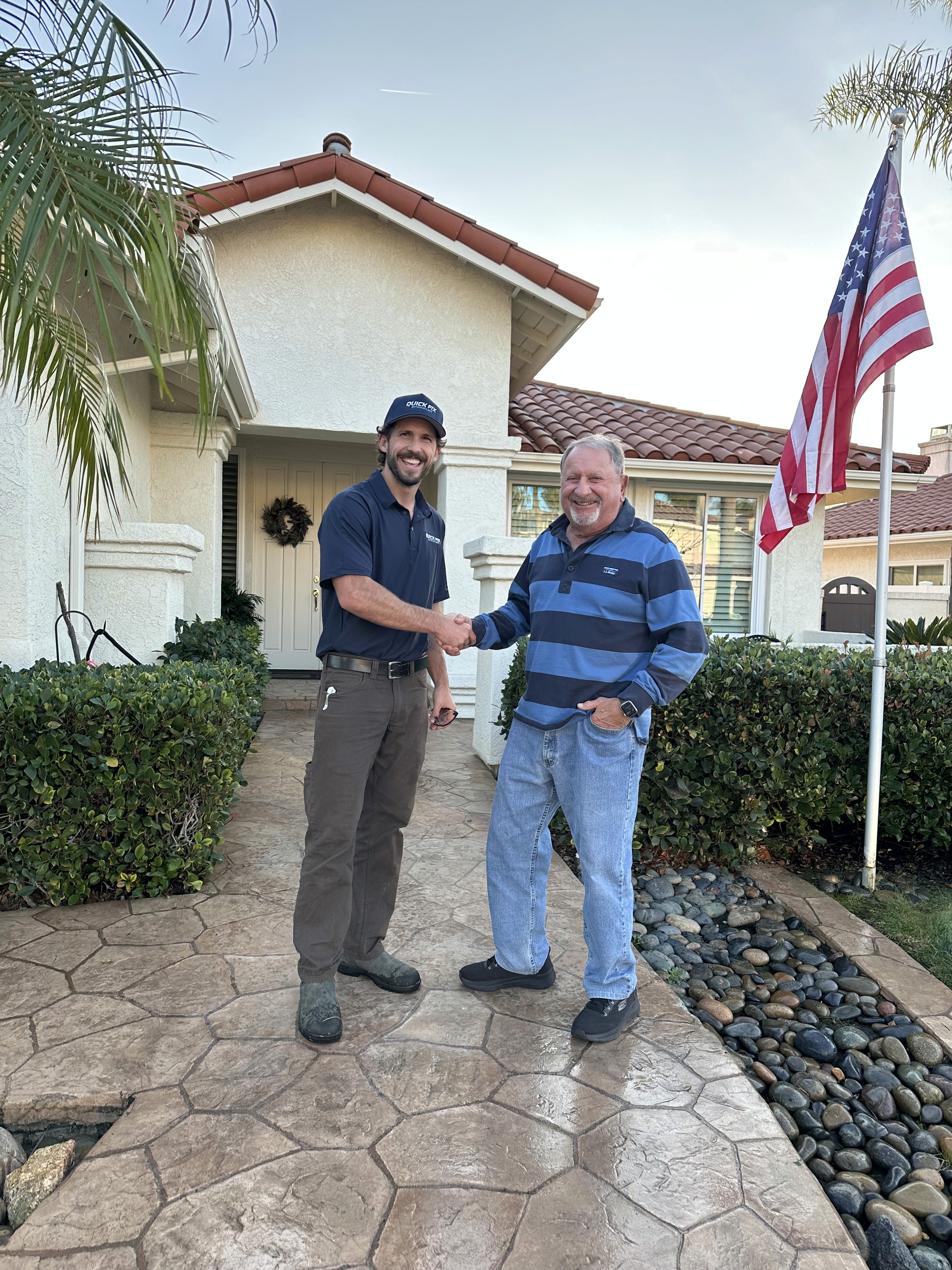 Owner Christian and customer Joe smiling in a front yard, representing a five-star service experience and successful sprinkler system repair.