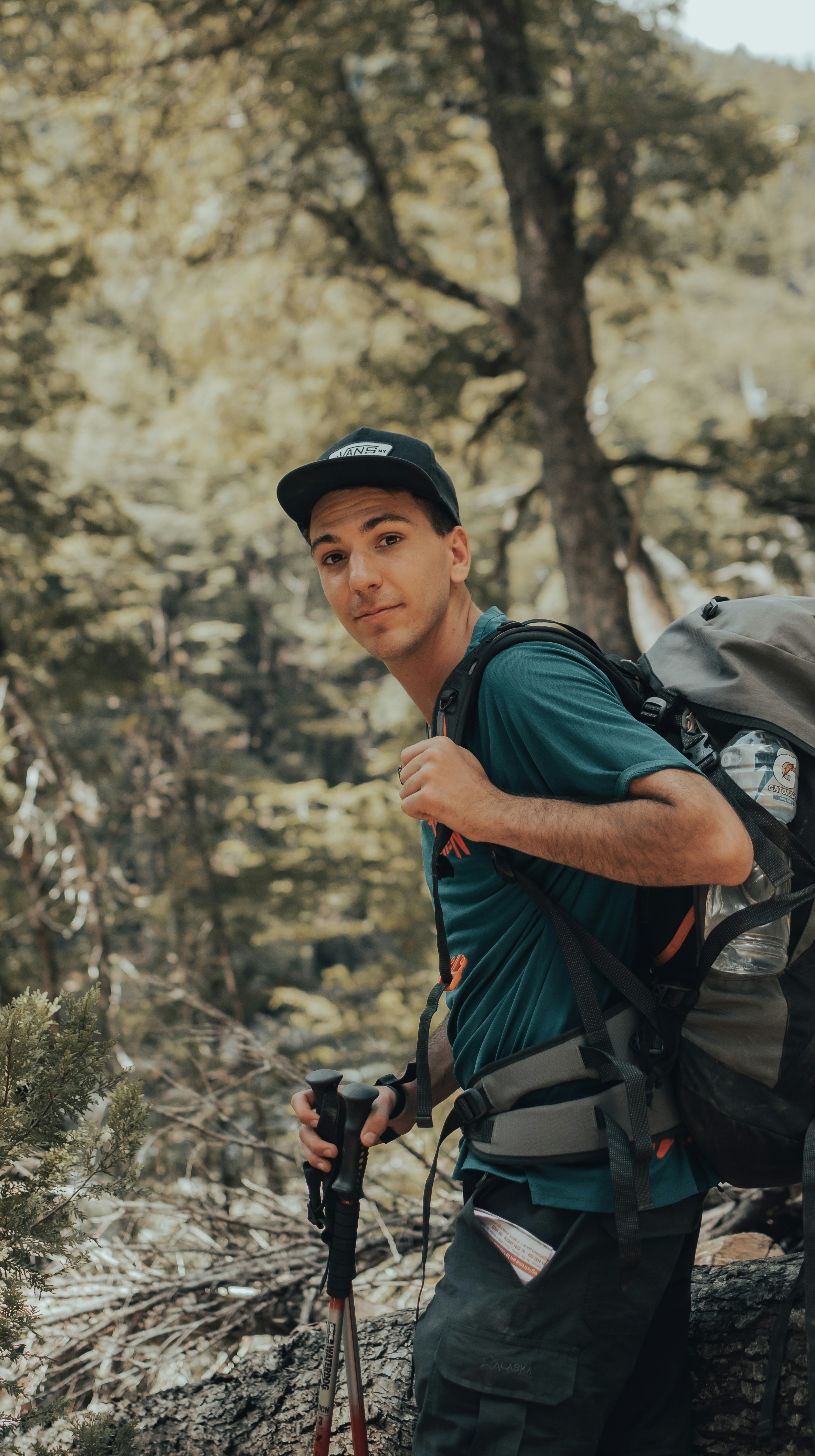 man in blue shirt and black cap holding gray backpack