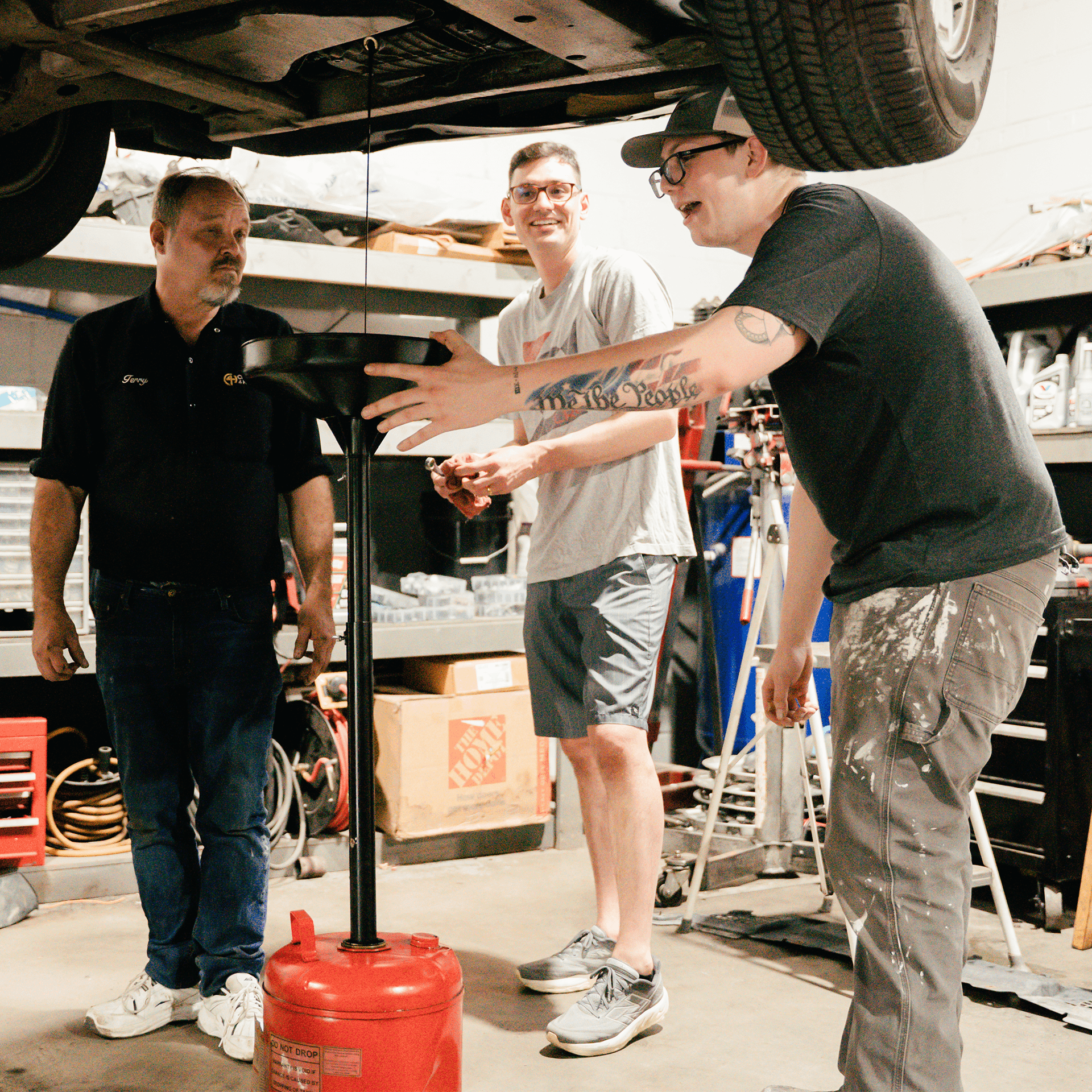 Three men changing oil on a car.