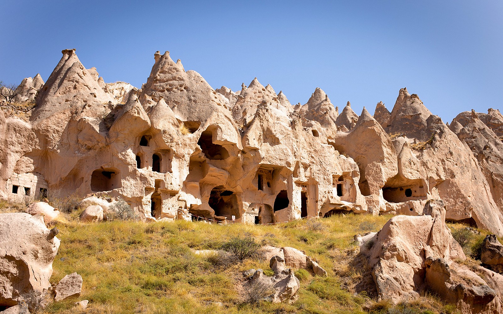 Cappadocia, Türkiye'deki antik kaya oluşumları ve mağara evleri, tertemiz mavi gökyüzünün altında.