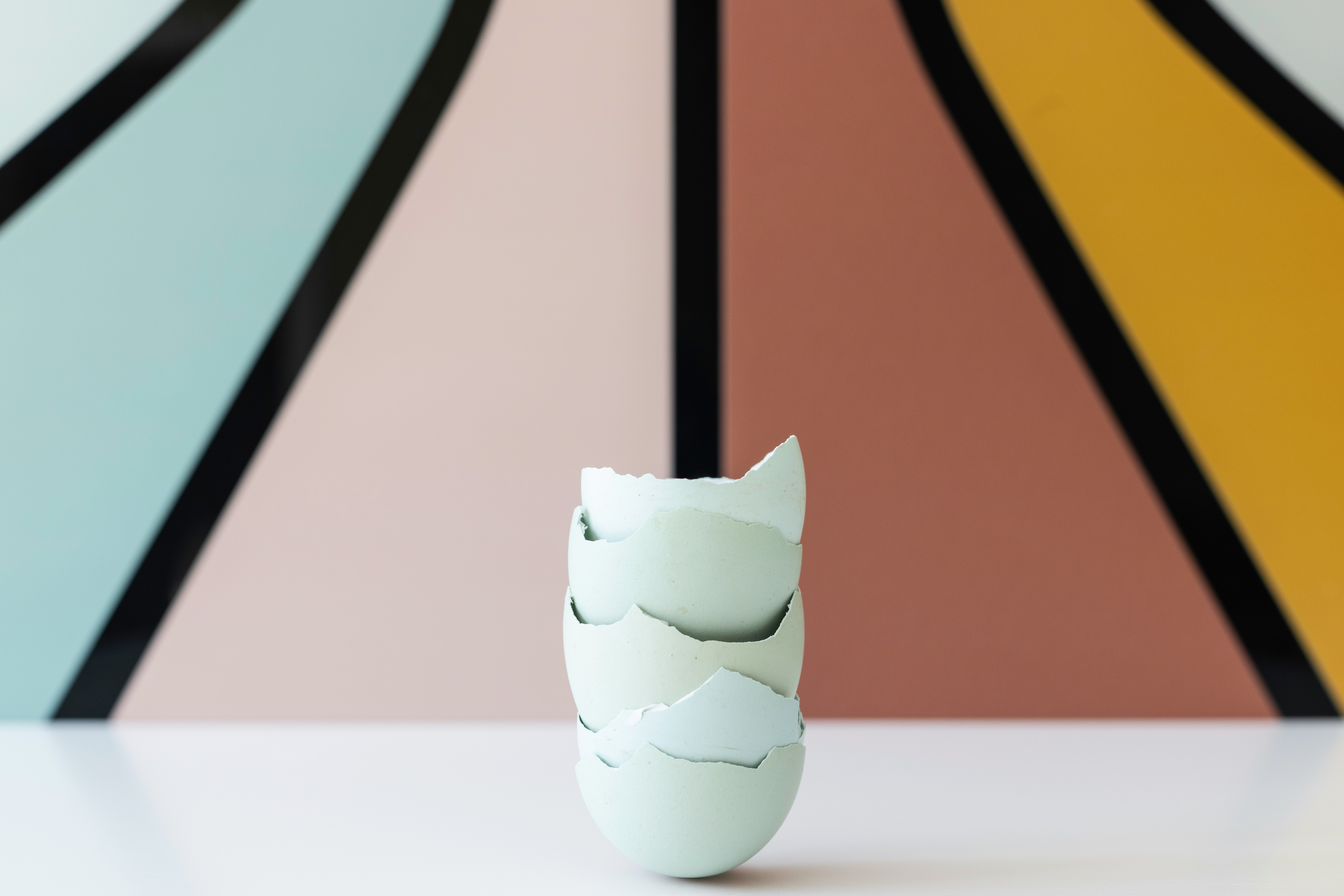 A white vase sitting in front of a colorful wall