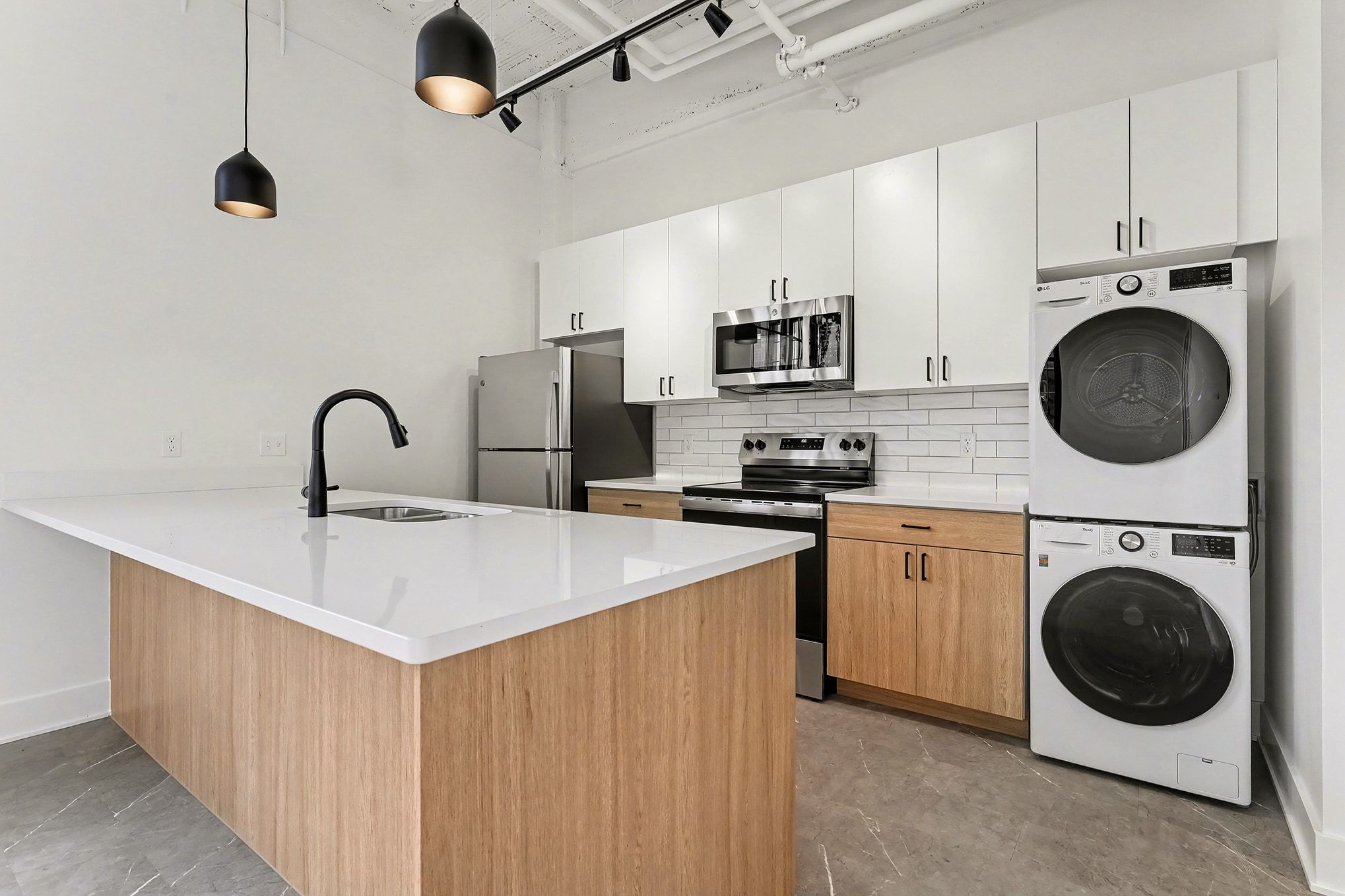 A large white building with a modern architectural design, featuring multiple windows and a clear blue sky in the background.