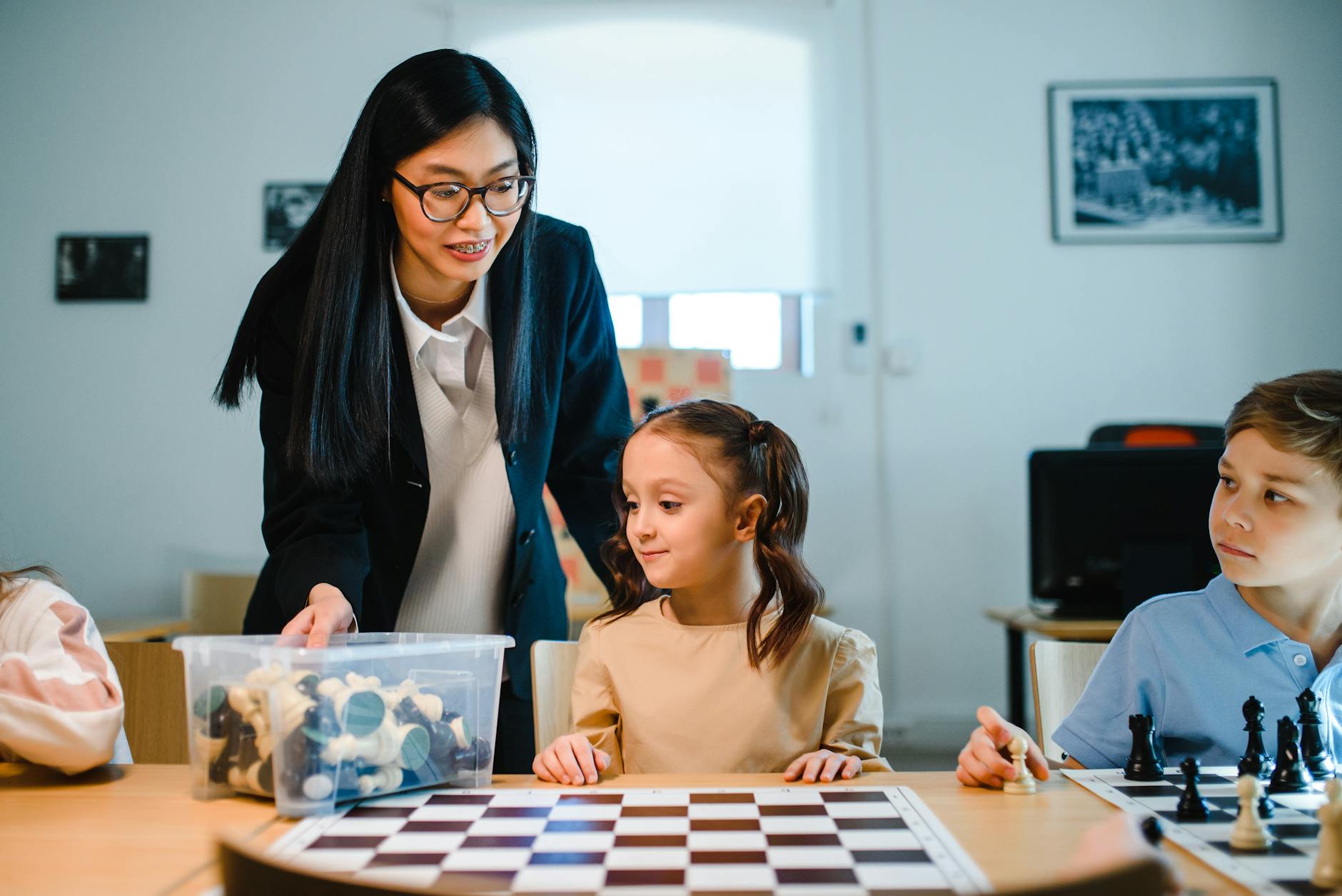 Three students laughing while playing an educational board game to practice their methods of teaching English.