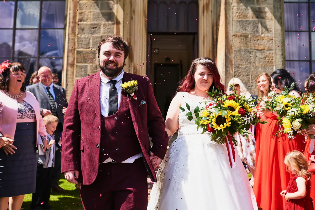 Couple walking out of Towneley Hall’s doorway as guests throw confetti
