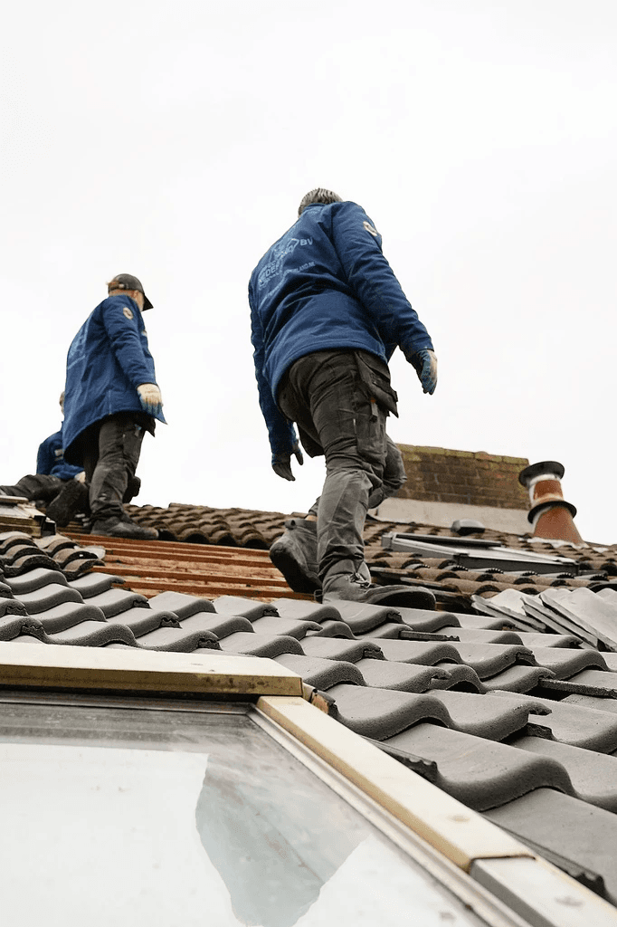 Mannen die op een dak staan en het dak renoveren