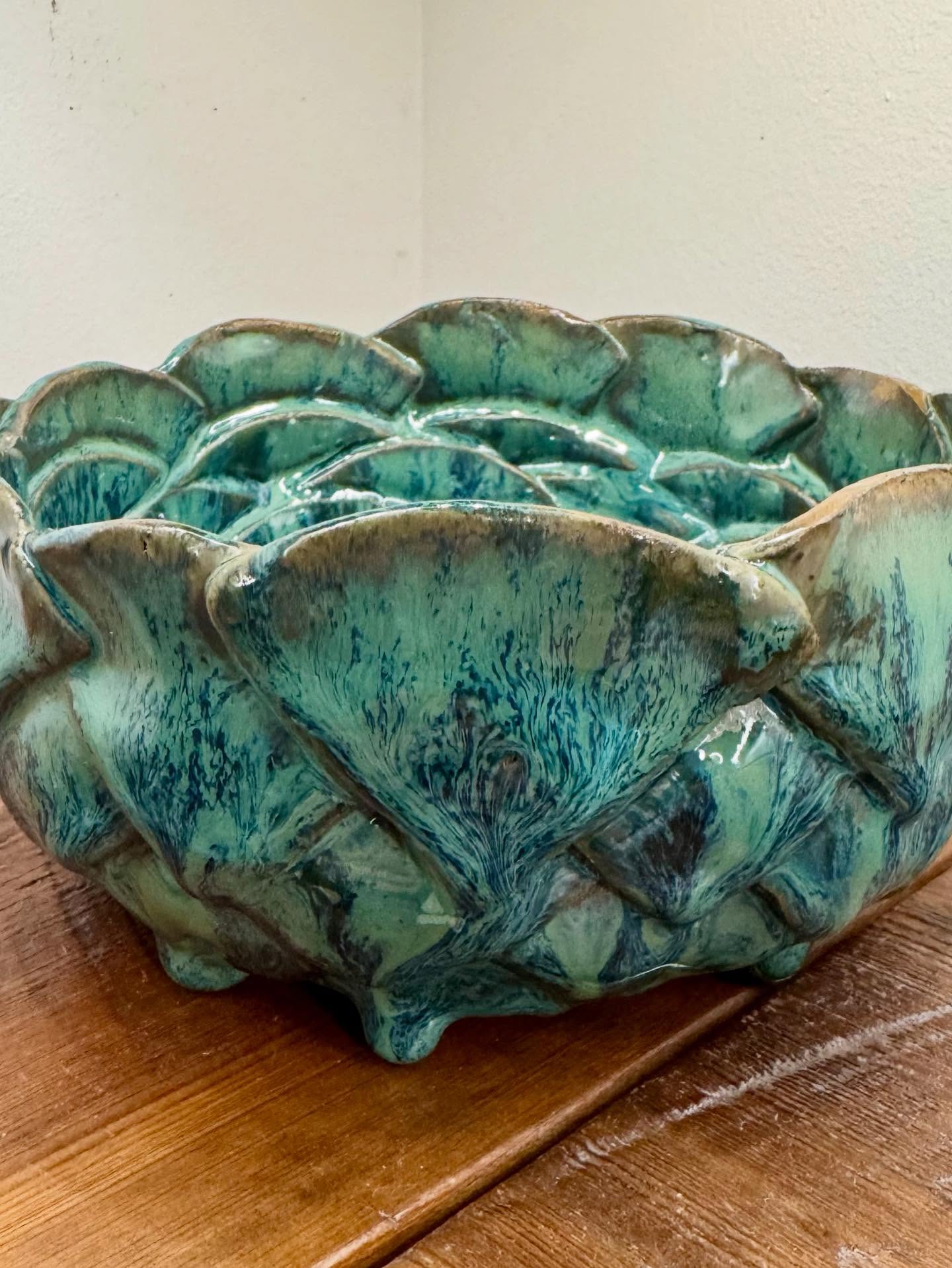 Large bowl of overlapping clay shapes in sea green with tan edges, on small feet.