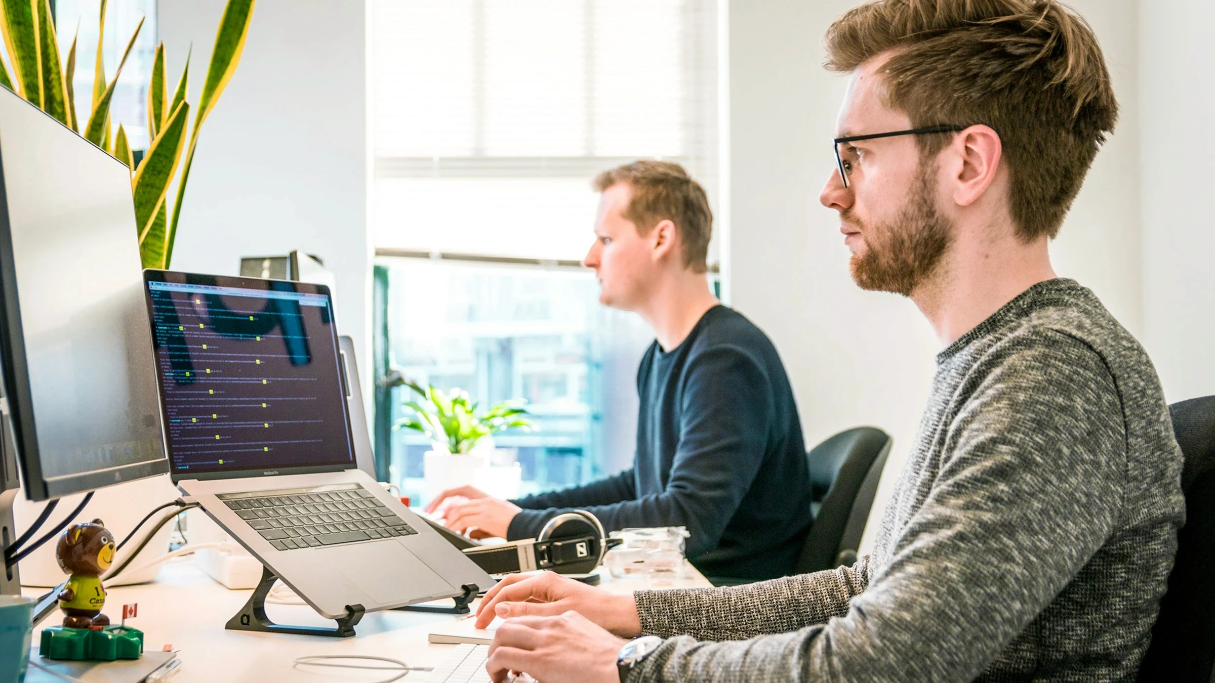 Two coworkers working at computers in a bright modern office.