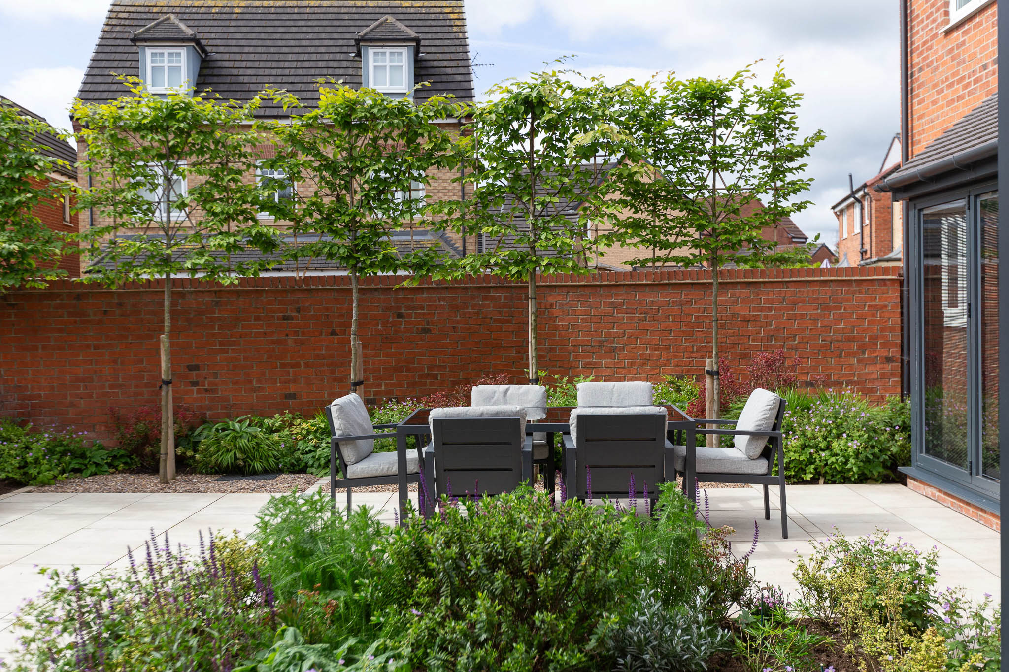 A lush garden scene with vibrant green leaves and delicate purple and white flowers blooming, set against a rustic wooden fence background.