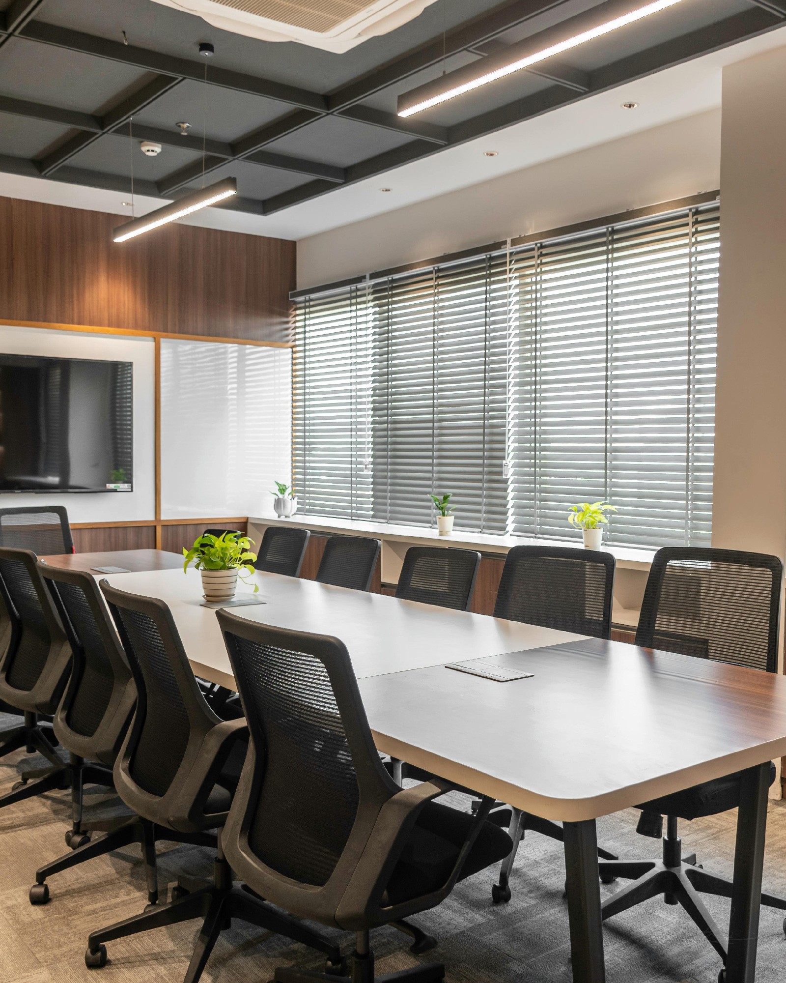 boardroom with long table, the room is empty, there is a TV mounted on the wall at the end of the table