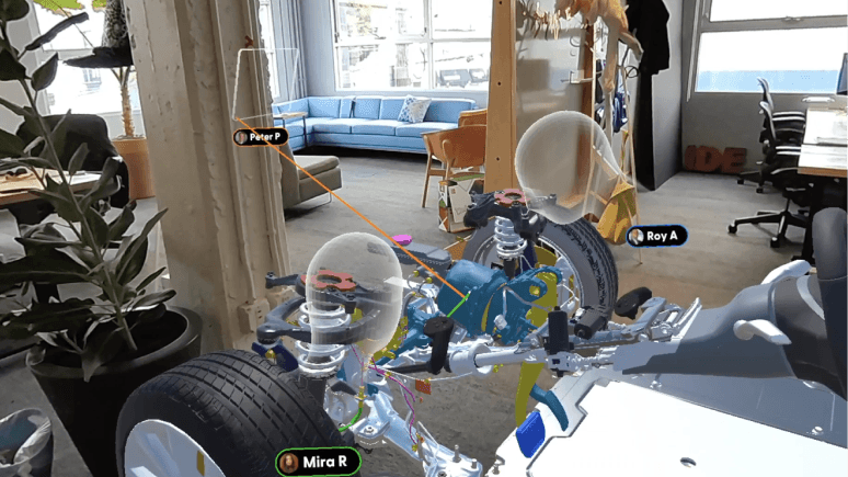 Multiple users in Campfire collaborate around a 3D automotive assembly, each represented by name tags and avatars within a shared mixed reality scene.