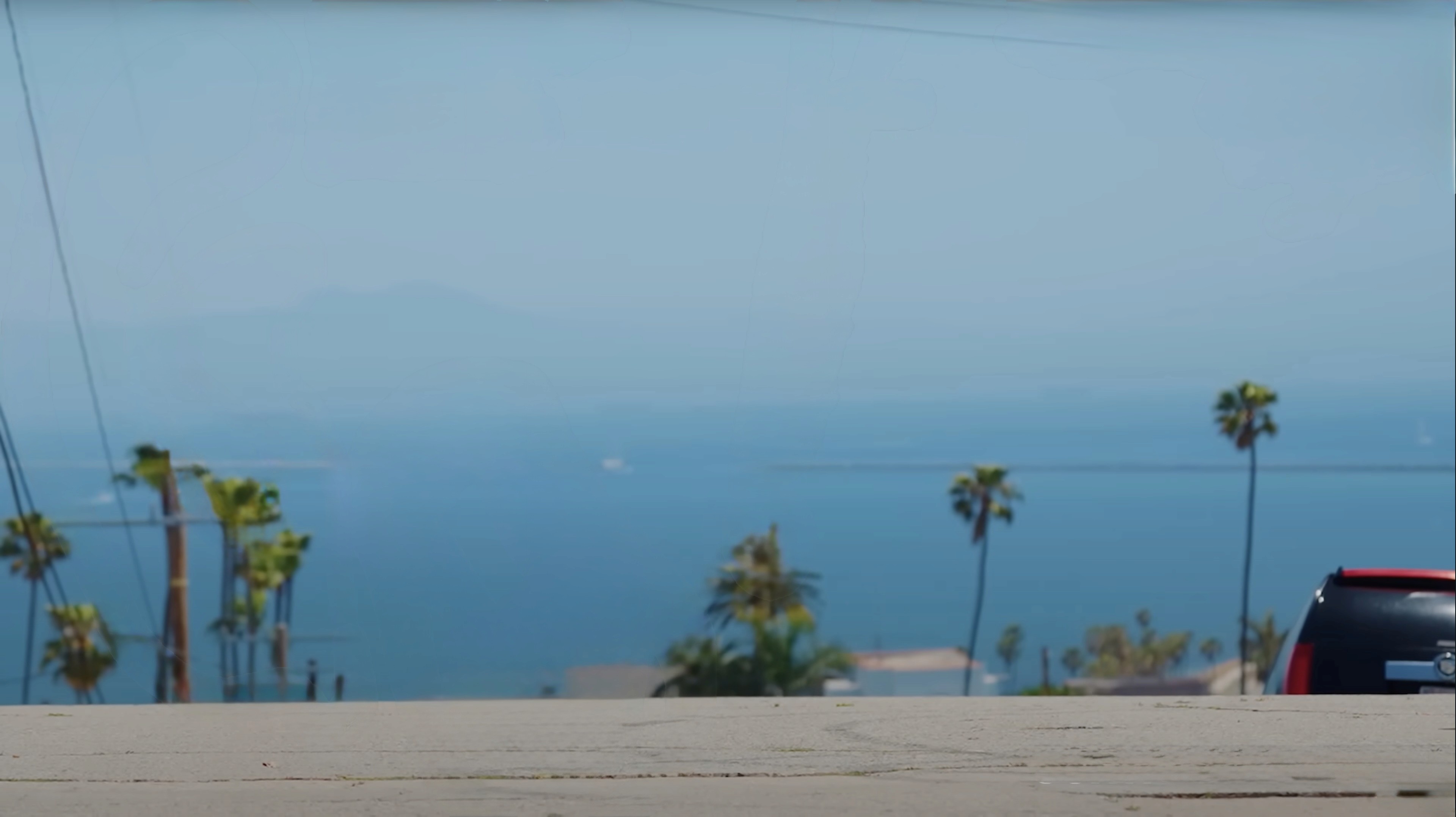 Cinematic shot of the LA skyline showing the ocean and palm trees.