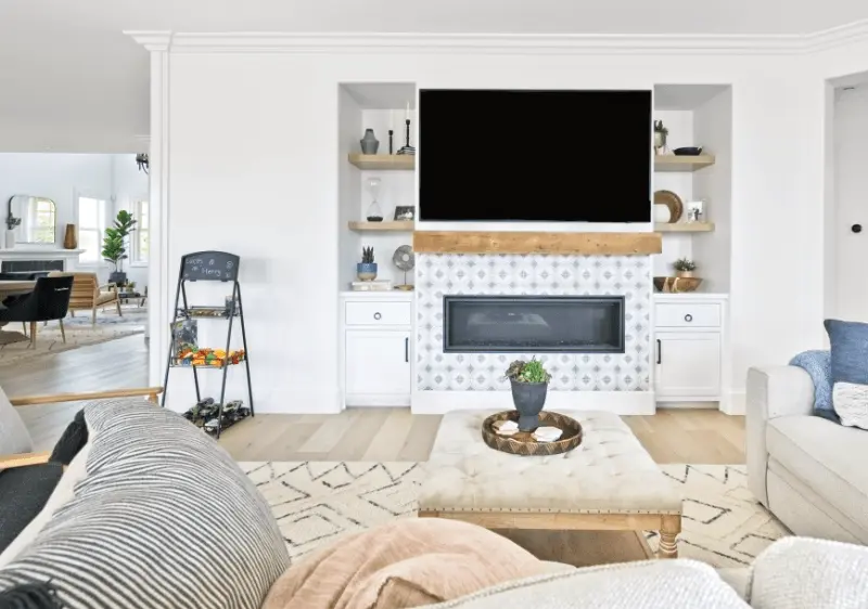 Wide perspective of the living room facing the fireplace, emphasizing the cozy and elegant design in the Dana Point Remodel. Photo by Todd Huge.