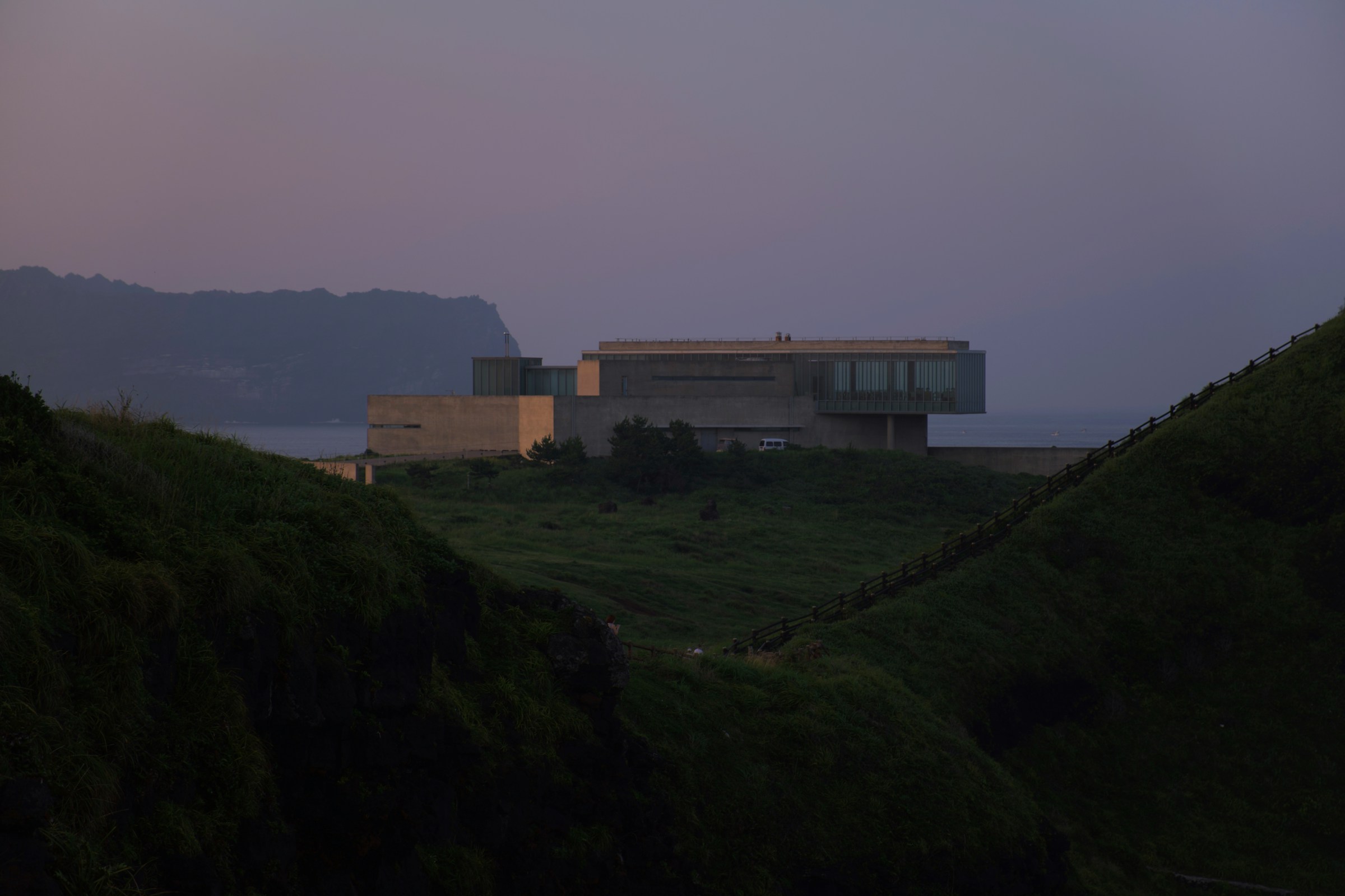 Headland Retreat, white and brown concrete building on green grass field under gray sky