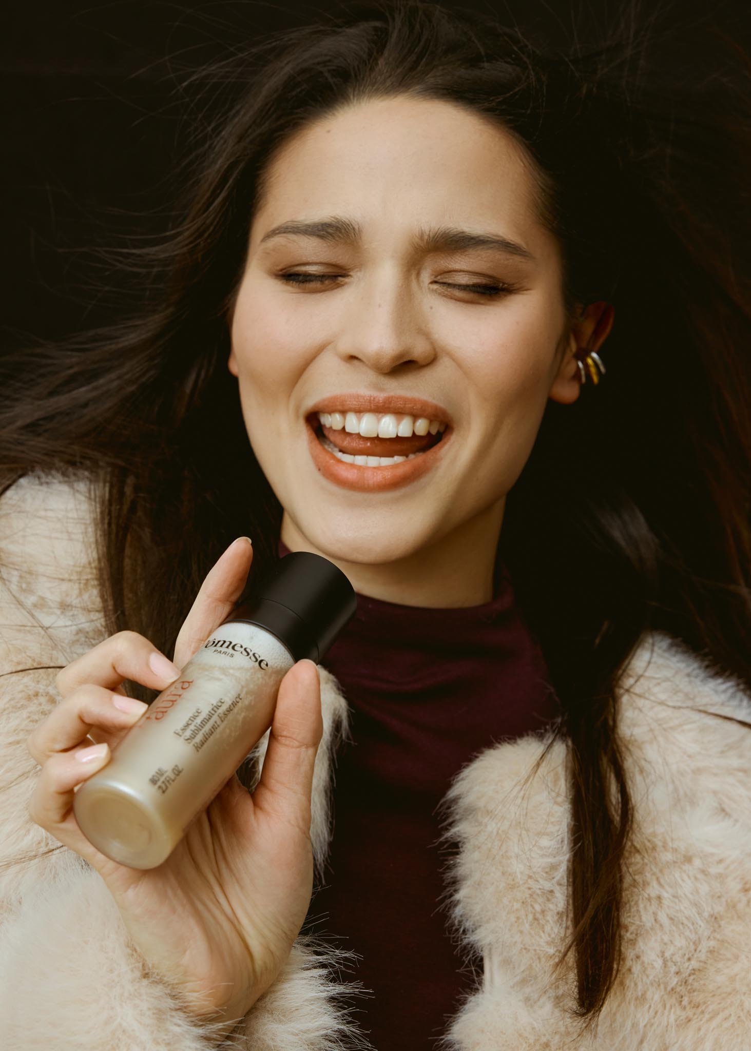 Femme souriante tenant un flacon de soin Pômesse Paris près de son visage