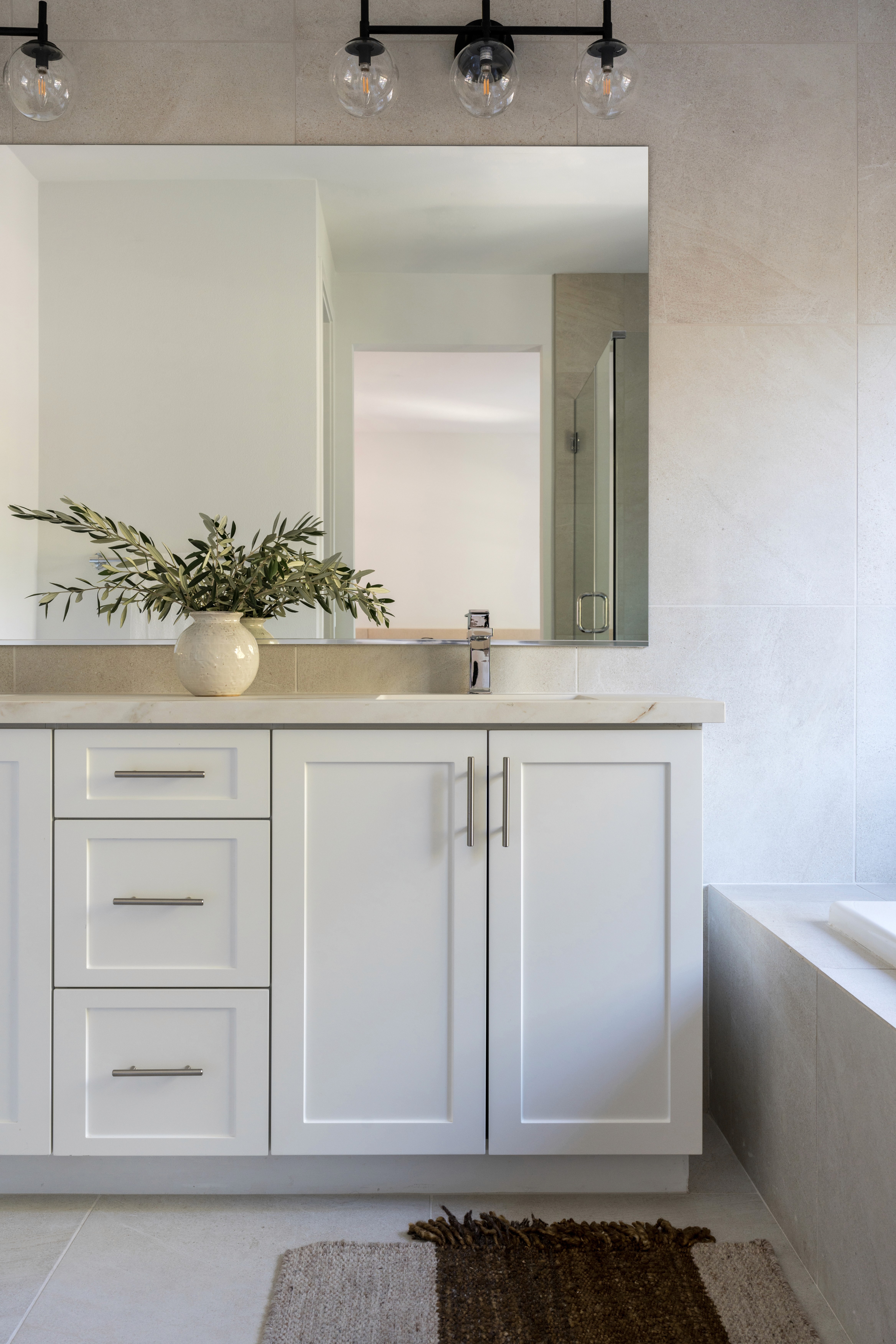 Primary bathroom with white cabinetry, brass finishes, and neutral elements by Jubilee Interiors in Arcadia, California