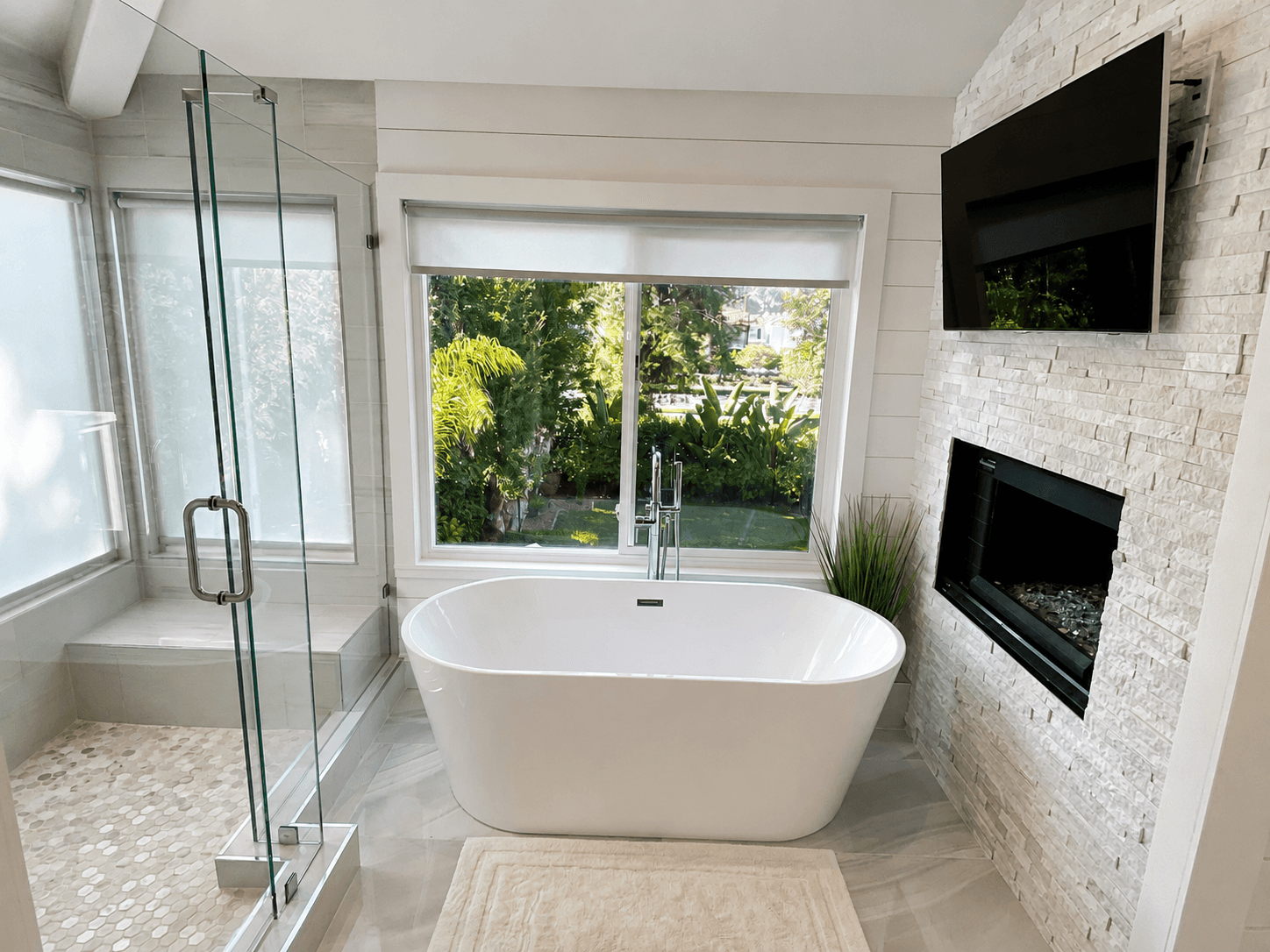 Modern indoor space with large glass doors, lush greenery, and a cozy seating area visible beyond.