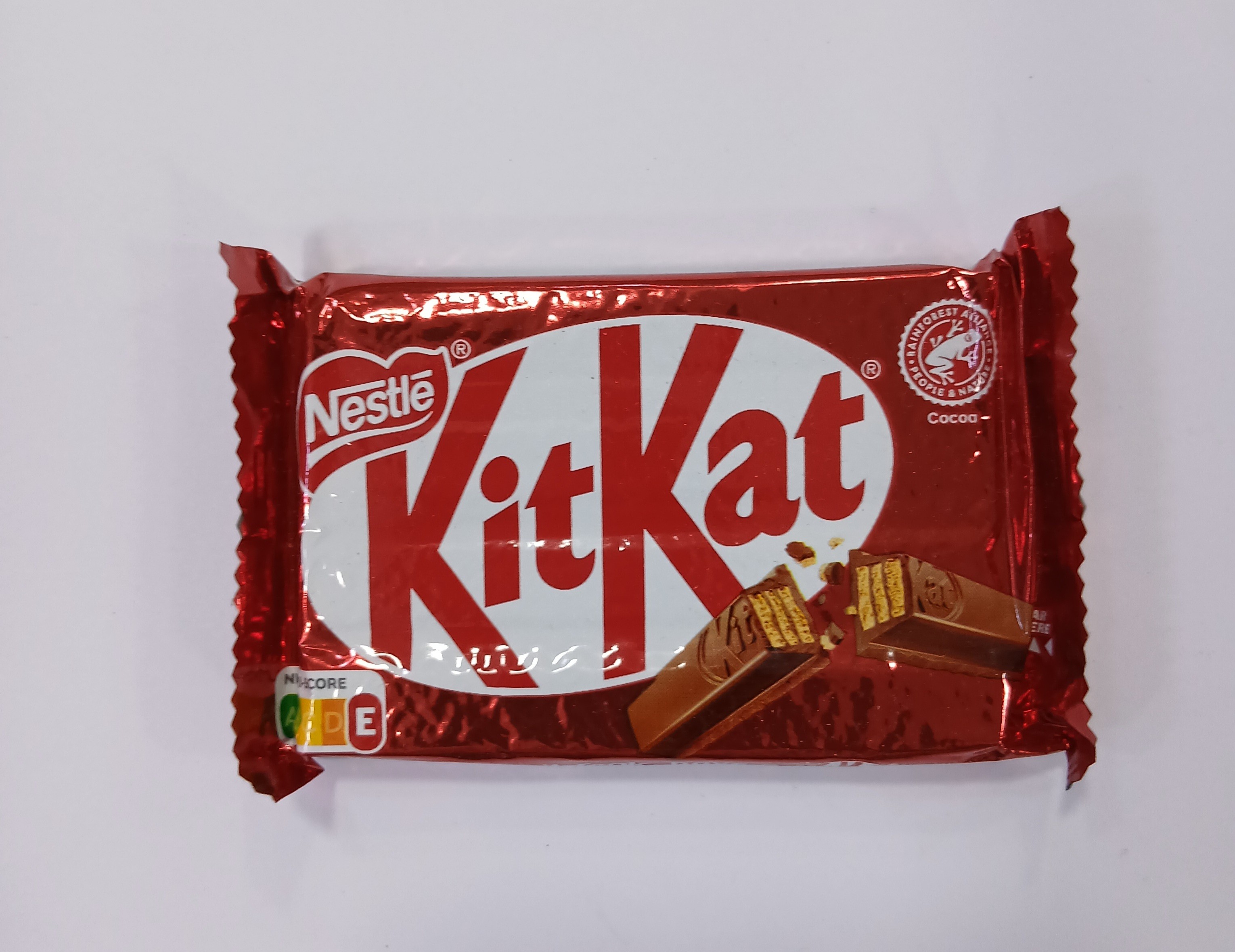 A red foil-wrapped packet with a clear plastic window shows four layered finger-shaped chocolate pieces inside.