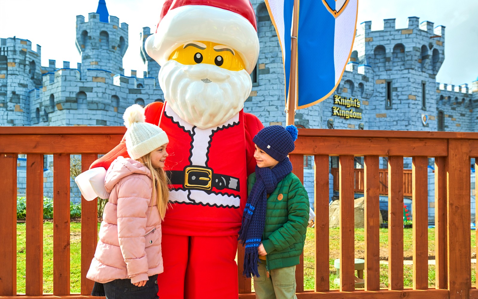 Children meeting Lego Santa at Legoland Christmas, London with castle backdrop.