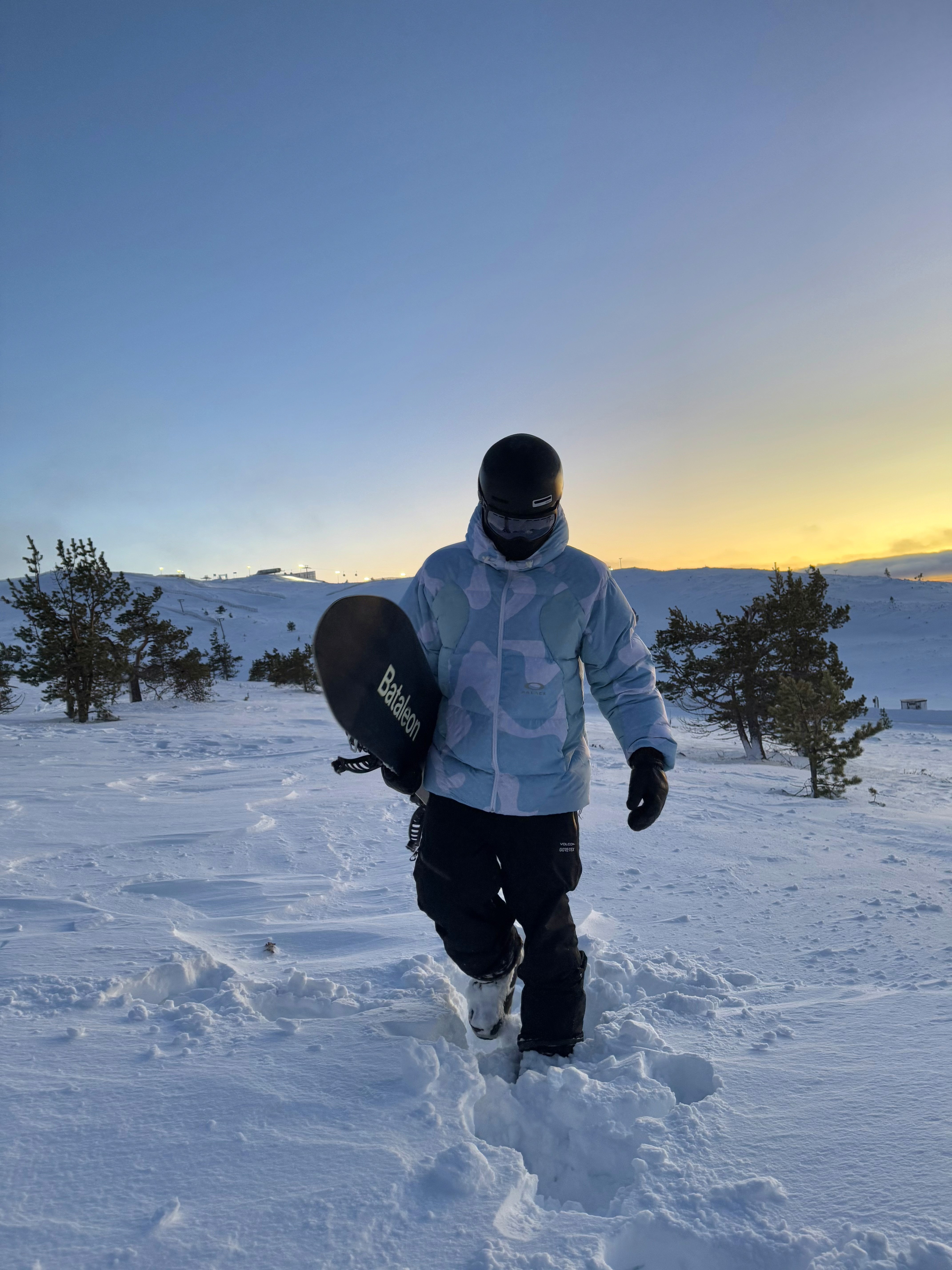 Walking in deep snow holding a bataleon snowboard in Lapland Finland