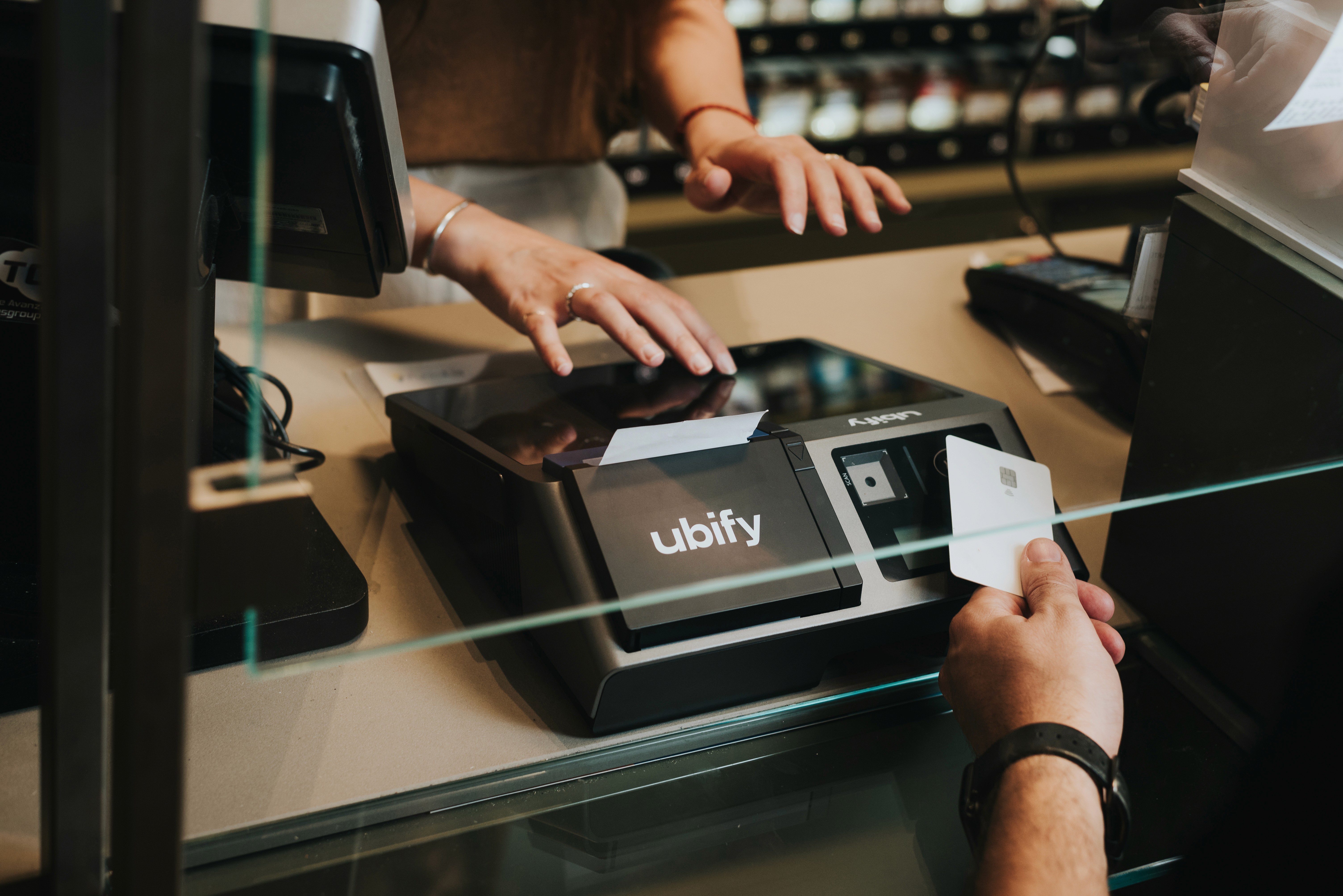 Commerciante utilizza la Cassa Ubify touchscreen mentre stampa uno scontrino, su bancone di un punto vendita.