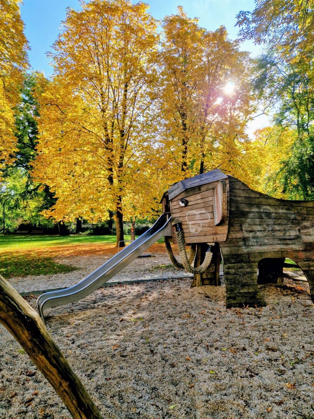Wooden mammoth with a slide as its trunk on the playground next to the Museum of Prehistory and Early History, in autumn leaves