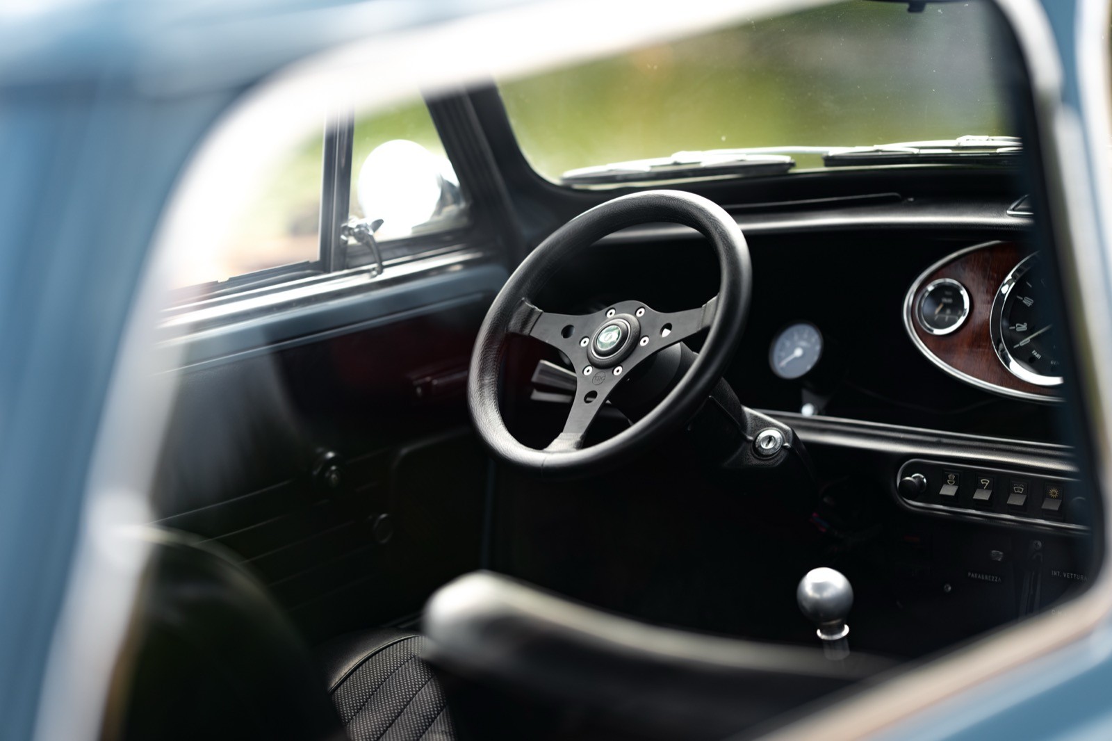 Close-up of a vintage car's interior featuring a classic steering wheel and dashboard details.