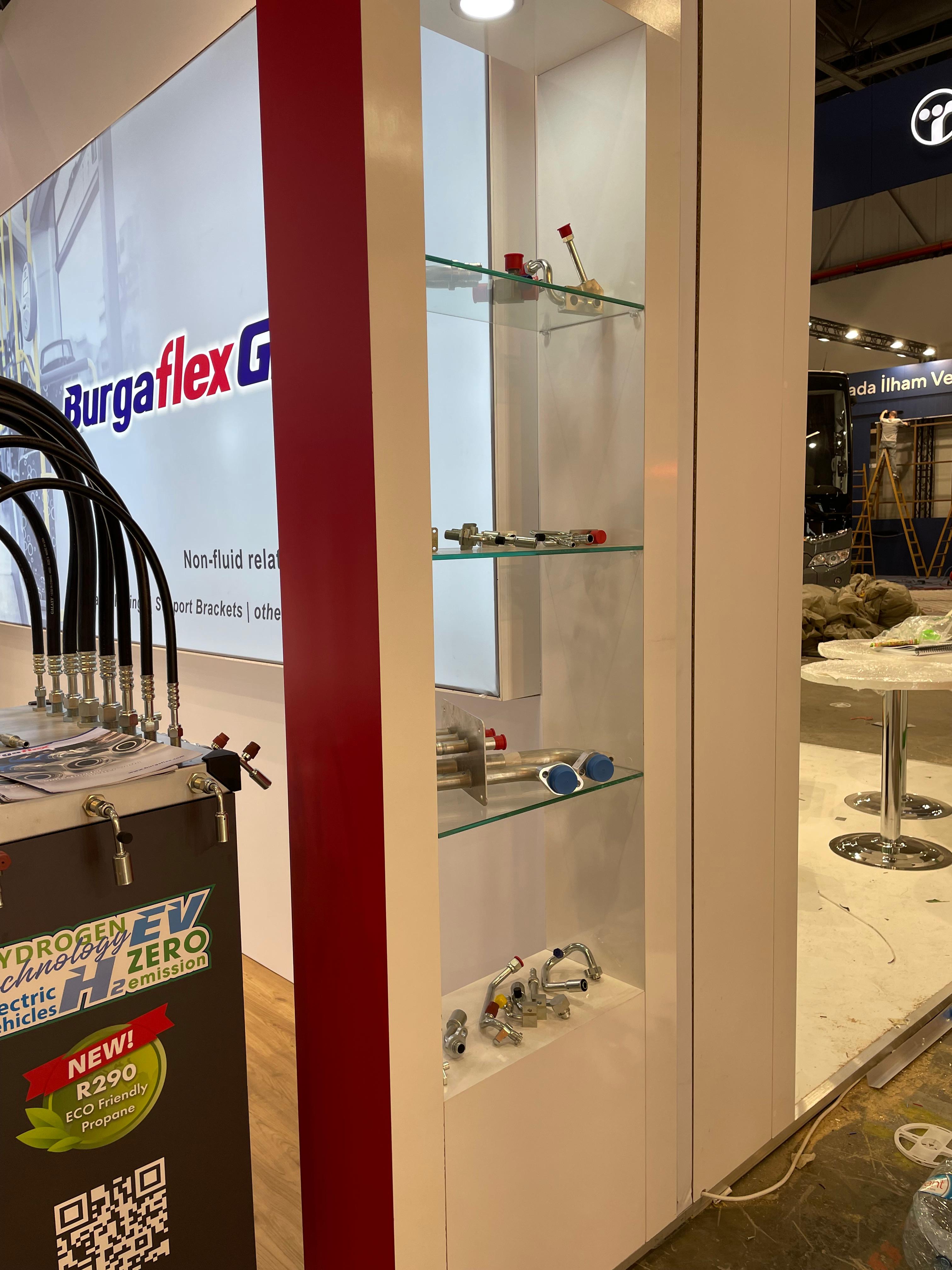 Product demonstration podiums at the Burgaflex stand, displaying real tubing, fittings, and hose assemblies for visitor interaction.