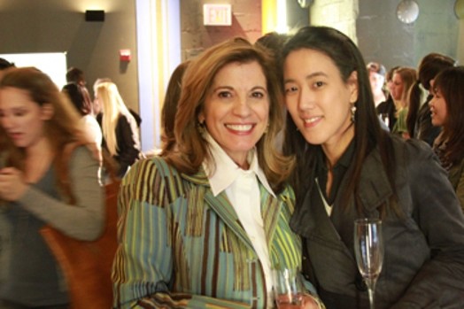 A photo of two women sitting among other people in a hall.