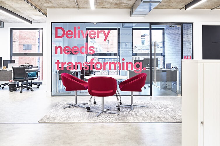 Modern office with glass wall slogan 'Delivery needs transforming