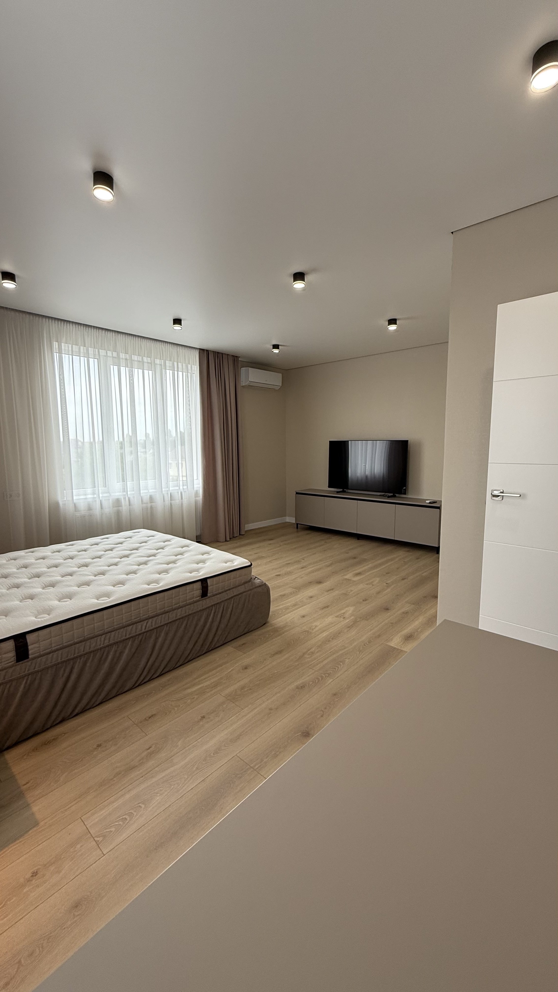 Простора спальня з великим ліжком, телевізором і кондиціонером