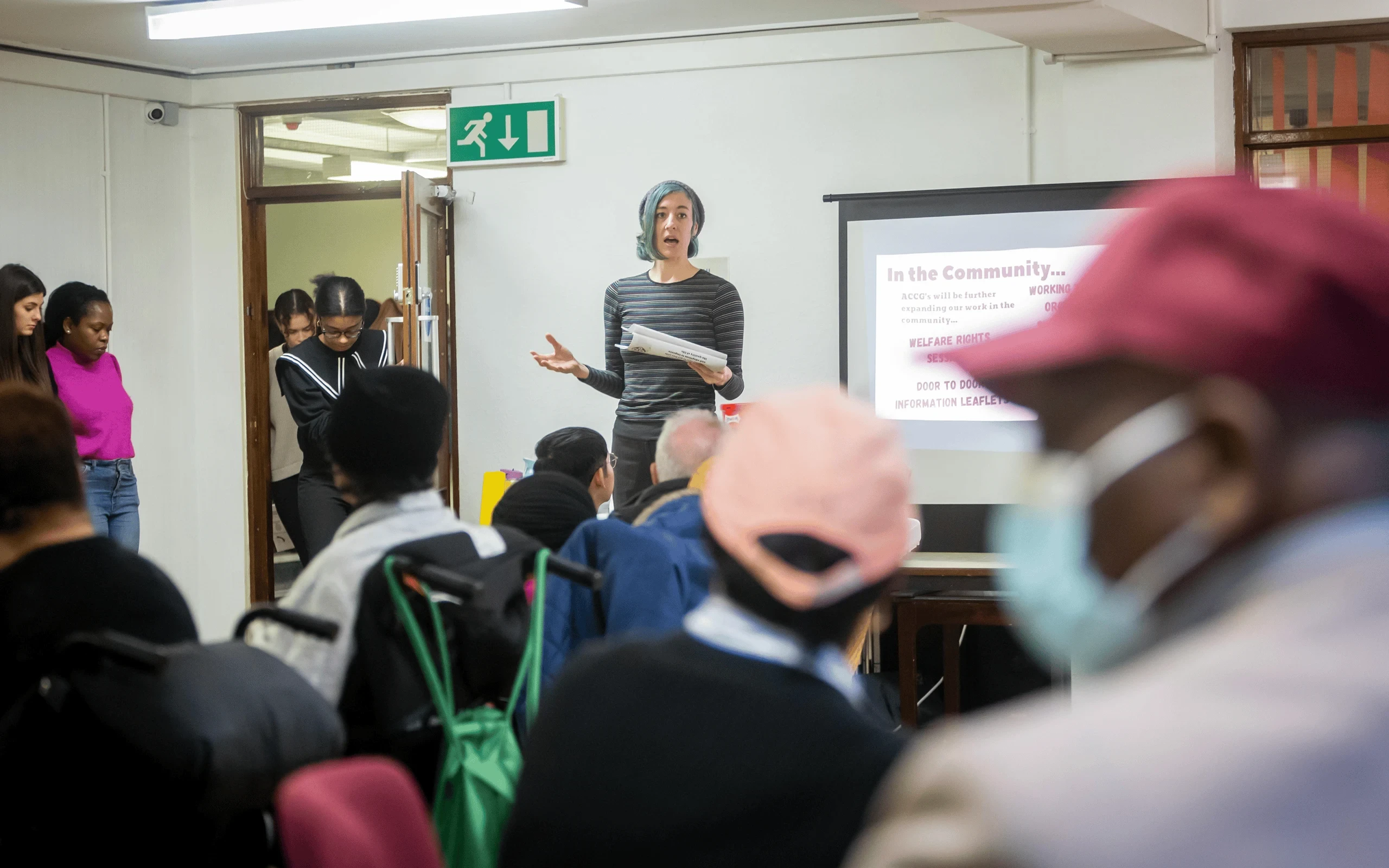 Speaker addressing a group of people in an indoor setting.