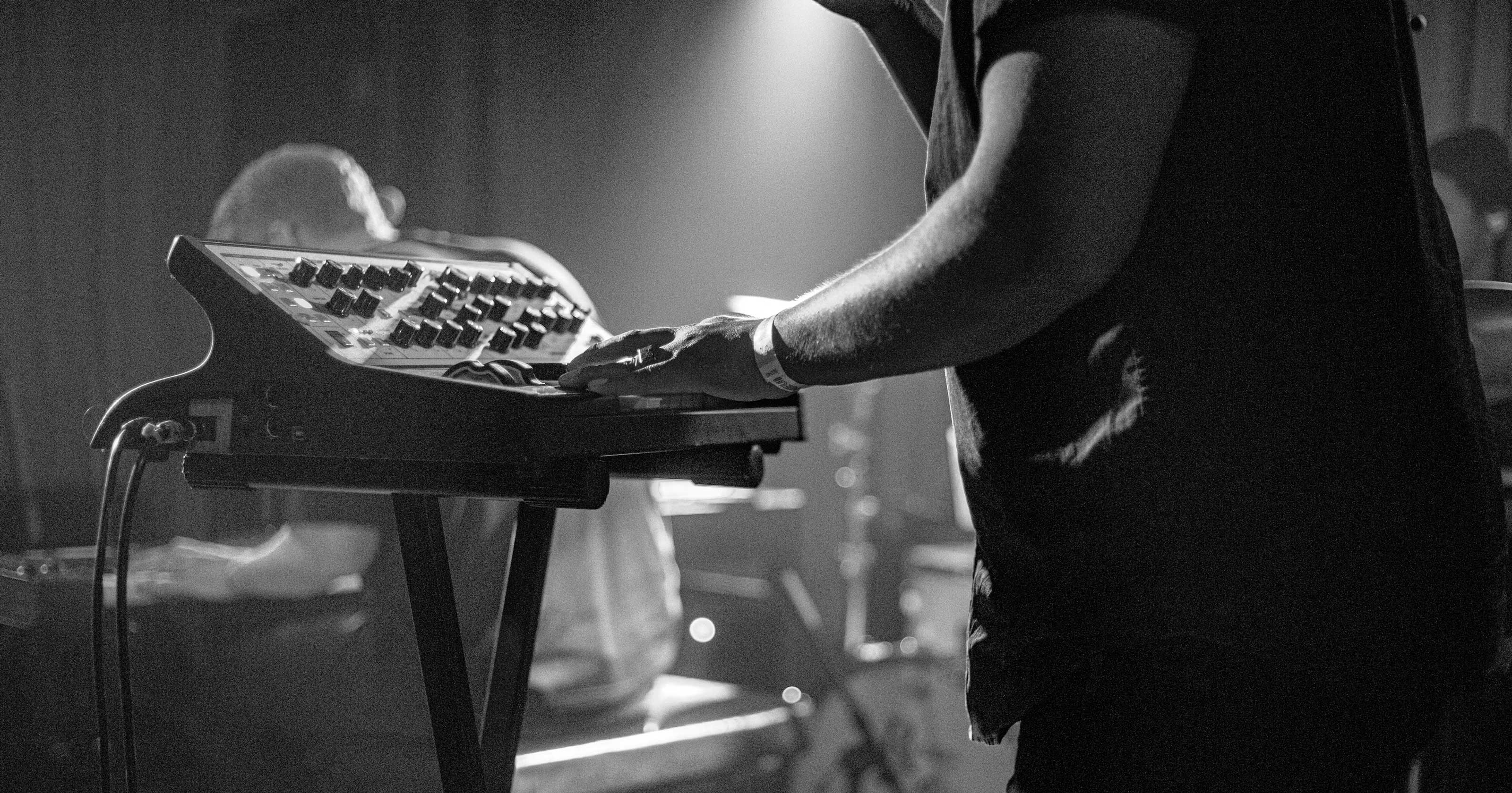 a black and white photo of a man using a synthesizer during a concert