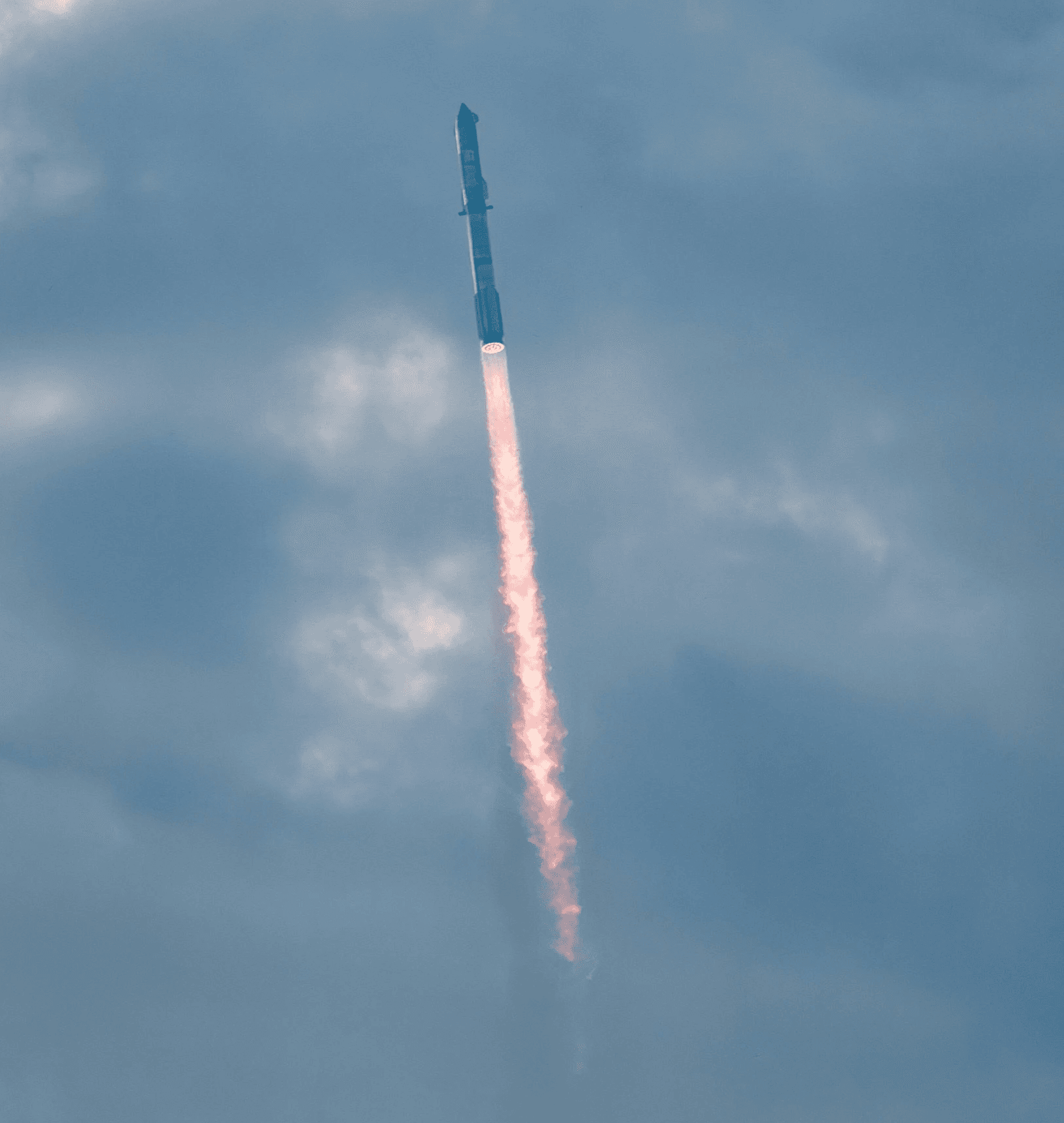 a jet flying through a cloudy blue sky