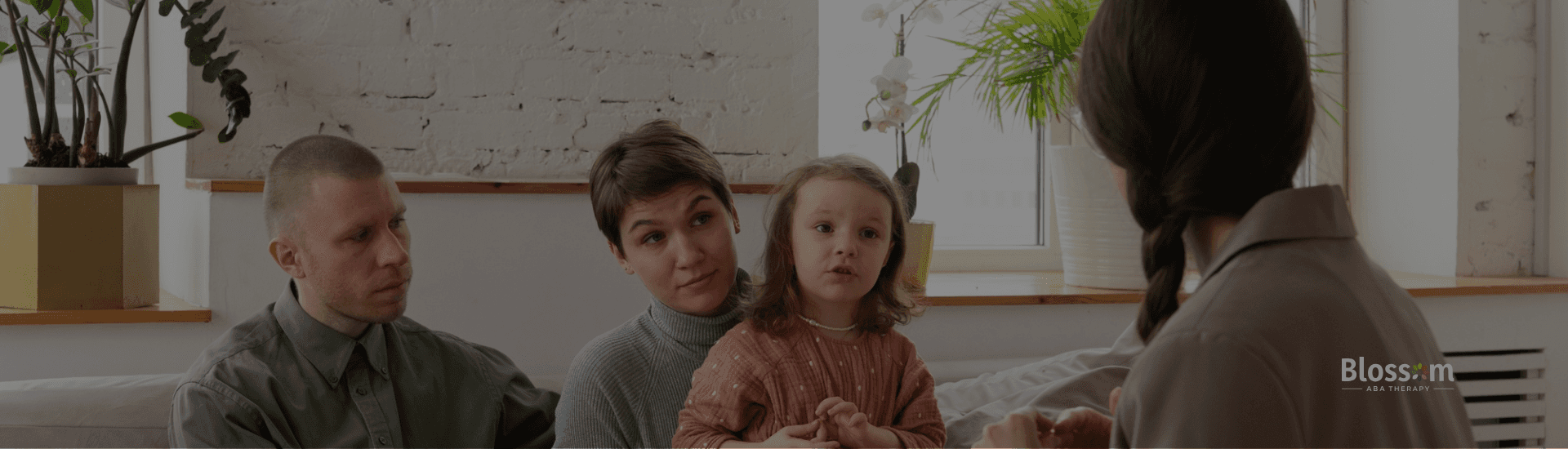 An ABA therapist is talking to a child with autism and her parents