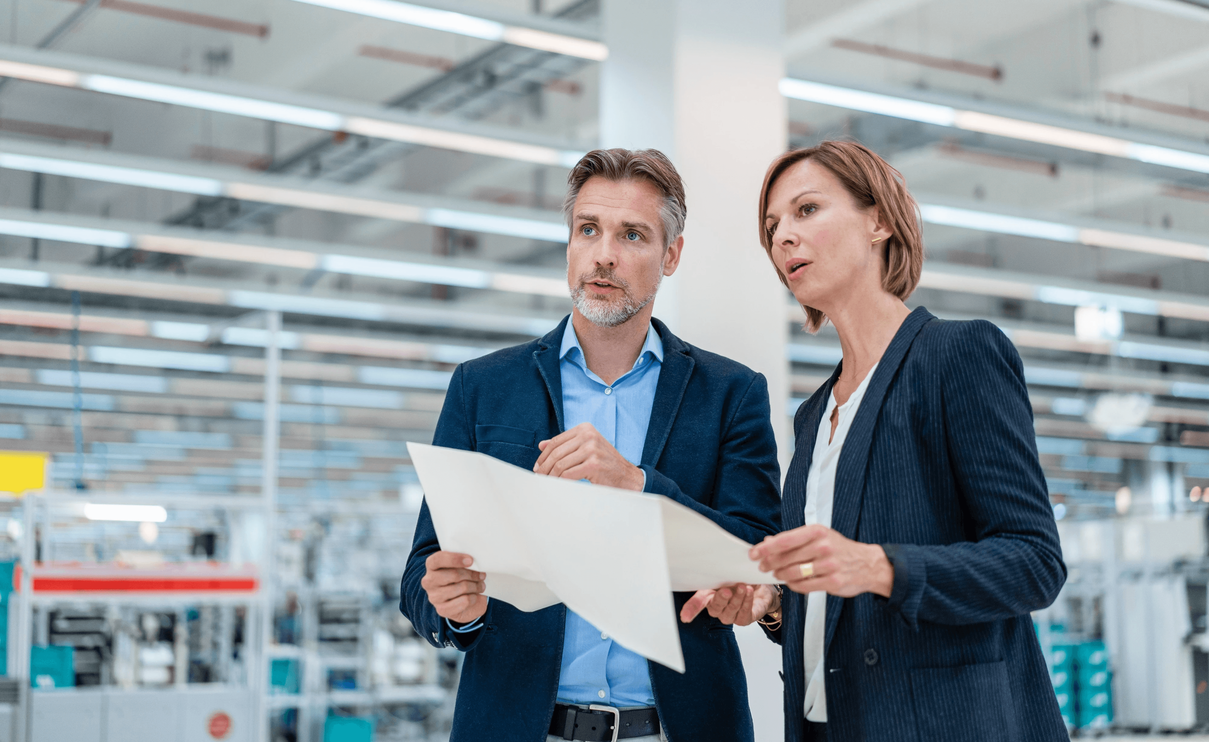 Interne Auditoren, die Dokumente in einem modernen Büroumfeld prüfen, repräsentieren die Prüfung des organisatorischen Kontexts, des Umfangs und der Systemgrenzen, um fundierte Sicherheit und auditbereite Managementsysteme zu etablieren.