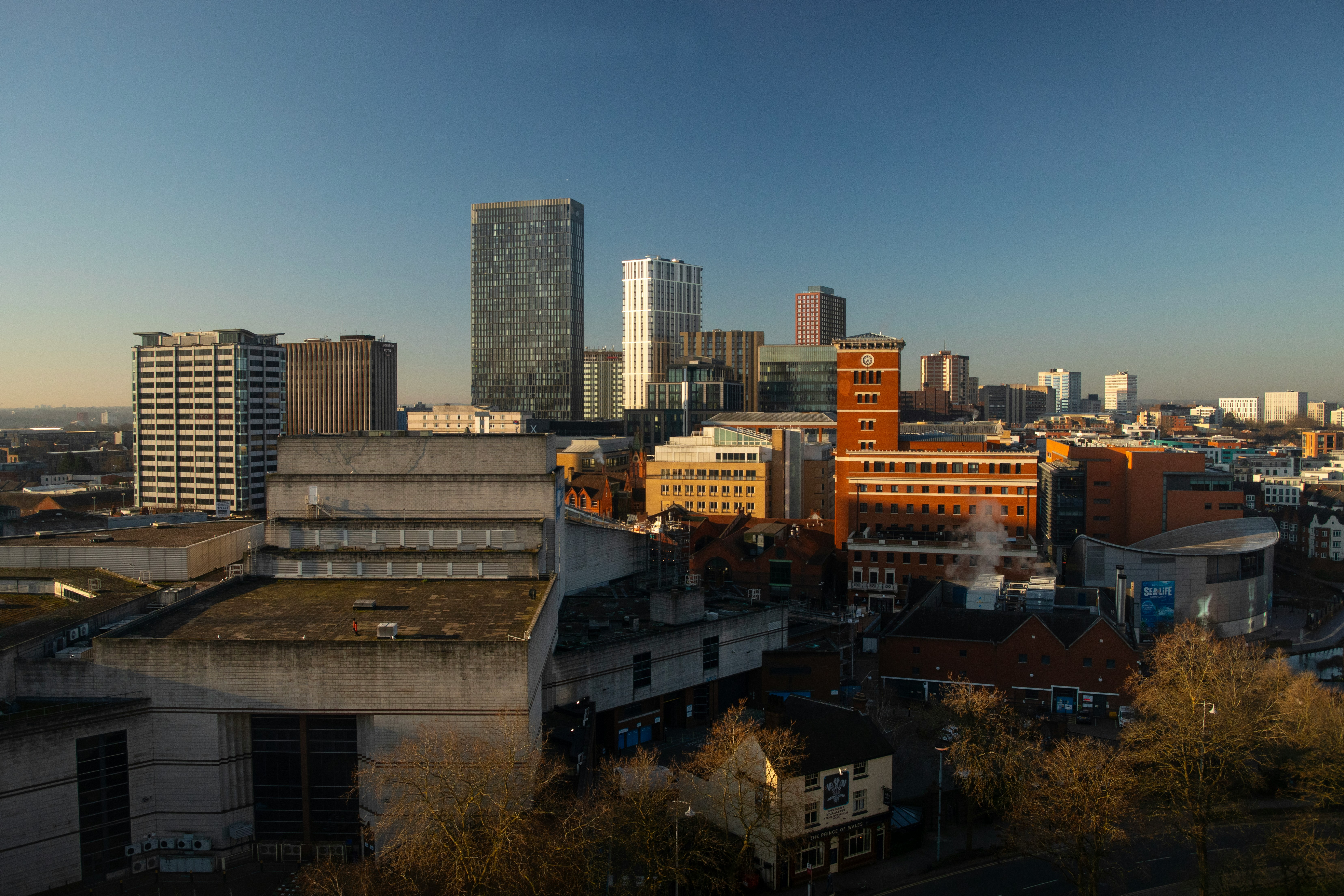Modern skyscrapers rise above older buildings in a city.