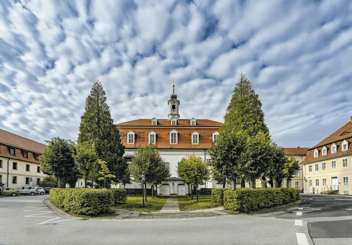 A cozy room with a wooden desk, computer, and warm sunlight streaming through a window.