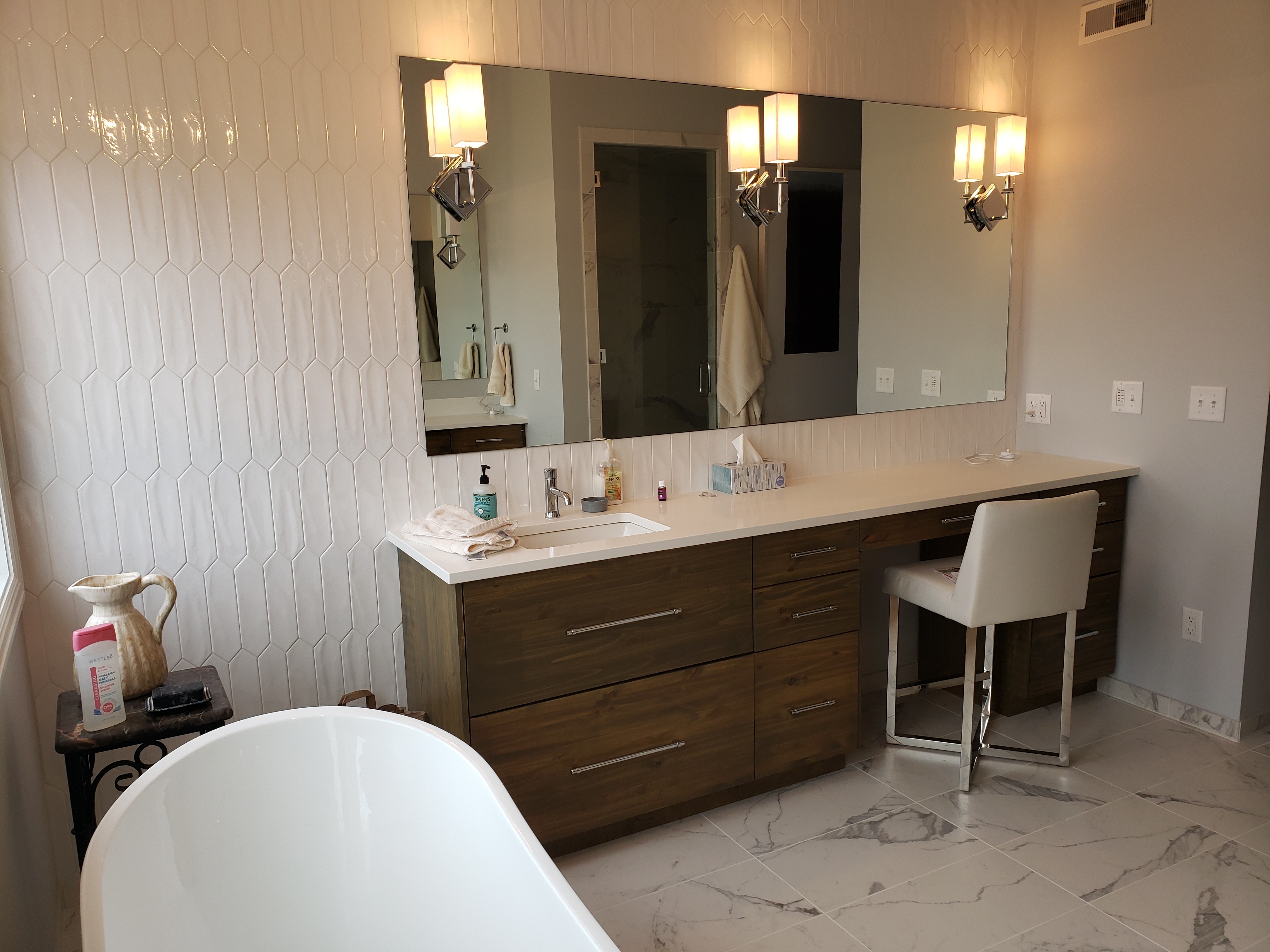 Modern bathroom featuring wooden cabinetry, a bathtub, a sleek sink, and natural light from a window.
