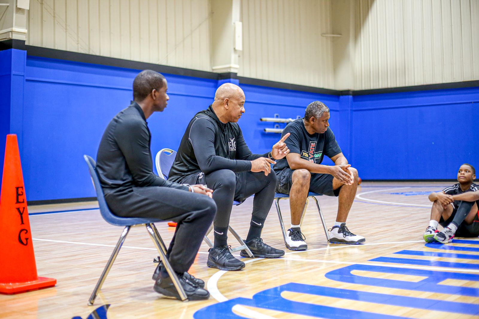 Coaches mentoring basketball players during a training session at Elevate Your Game gym.