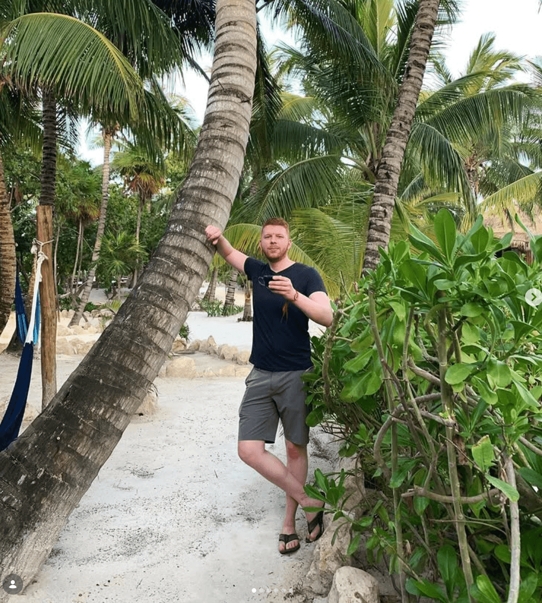 Erik Nowicki standing beside a palm tree while traveling